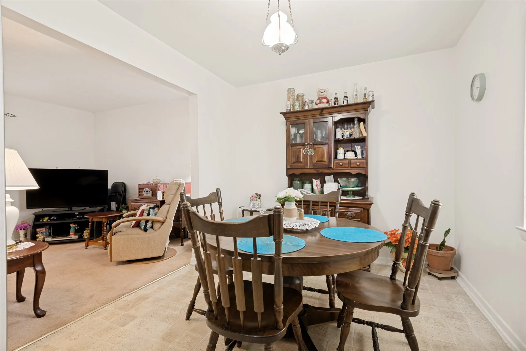 Dining area featuring neutral vinyl flooring, a cased opening, and a built-in wood hutch with glass doors