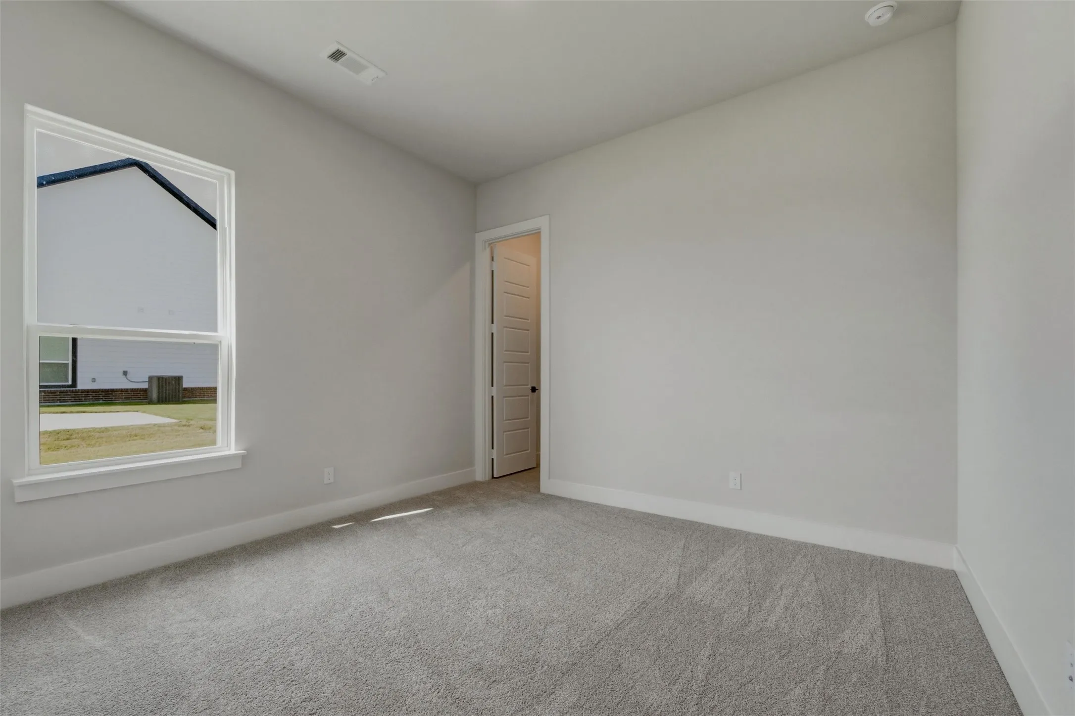 Light gray wall color, textured gray carpeting, white trim, recessed lighting, and a paneled door