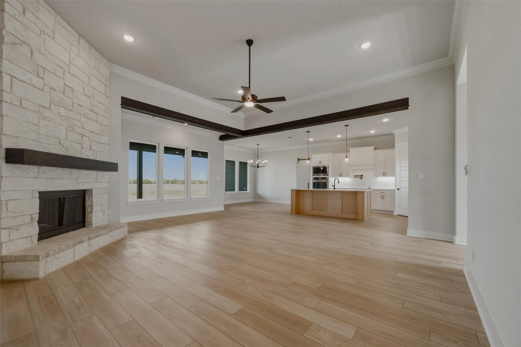 Spacious living area featuring light wood-finish flooring and a stone-clad fireplace