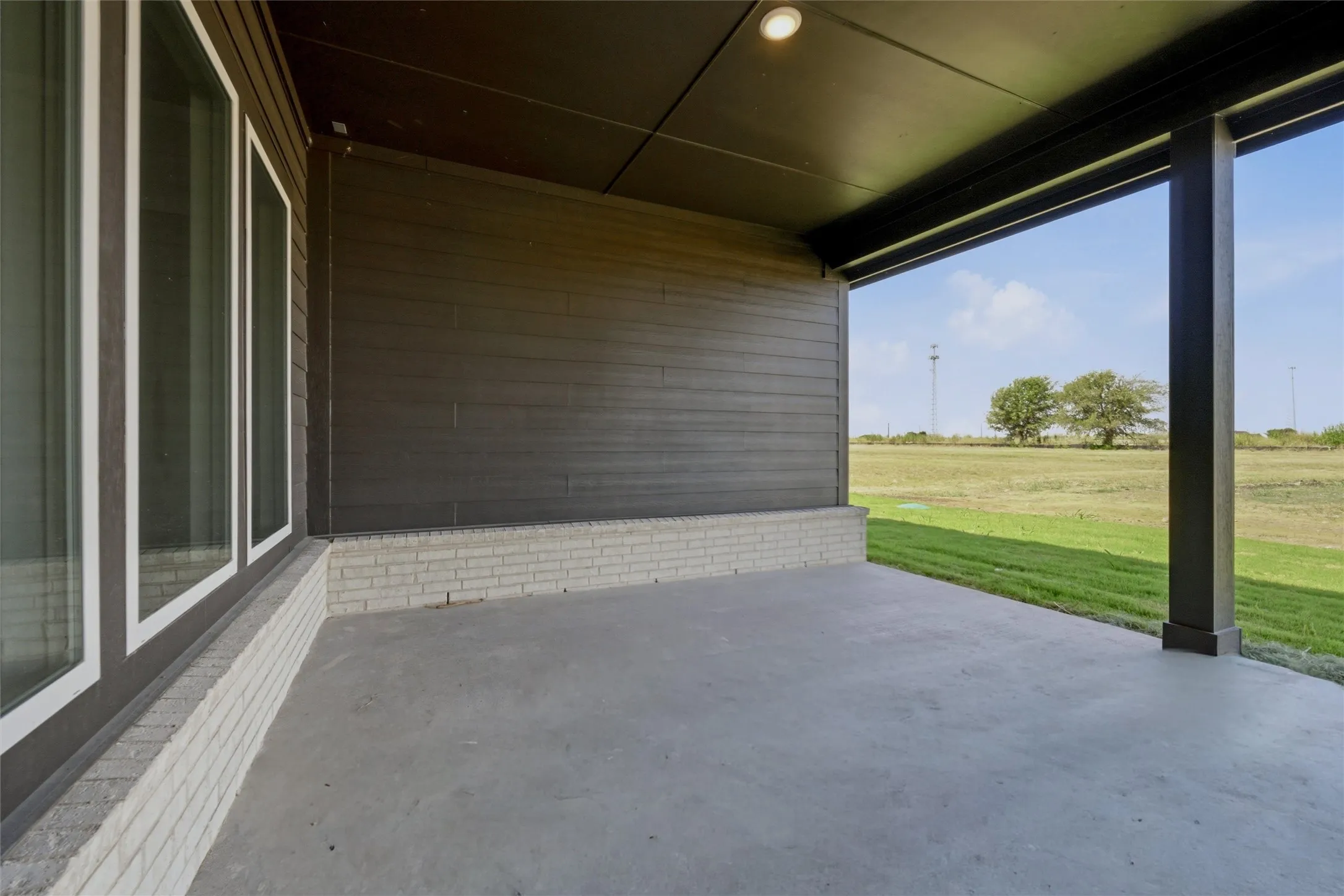 Covered patio with concrete flooring, recessed lighting, and a dark-toned siding exterior
