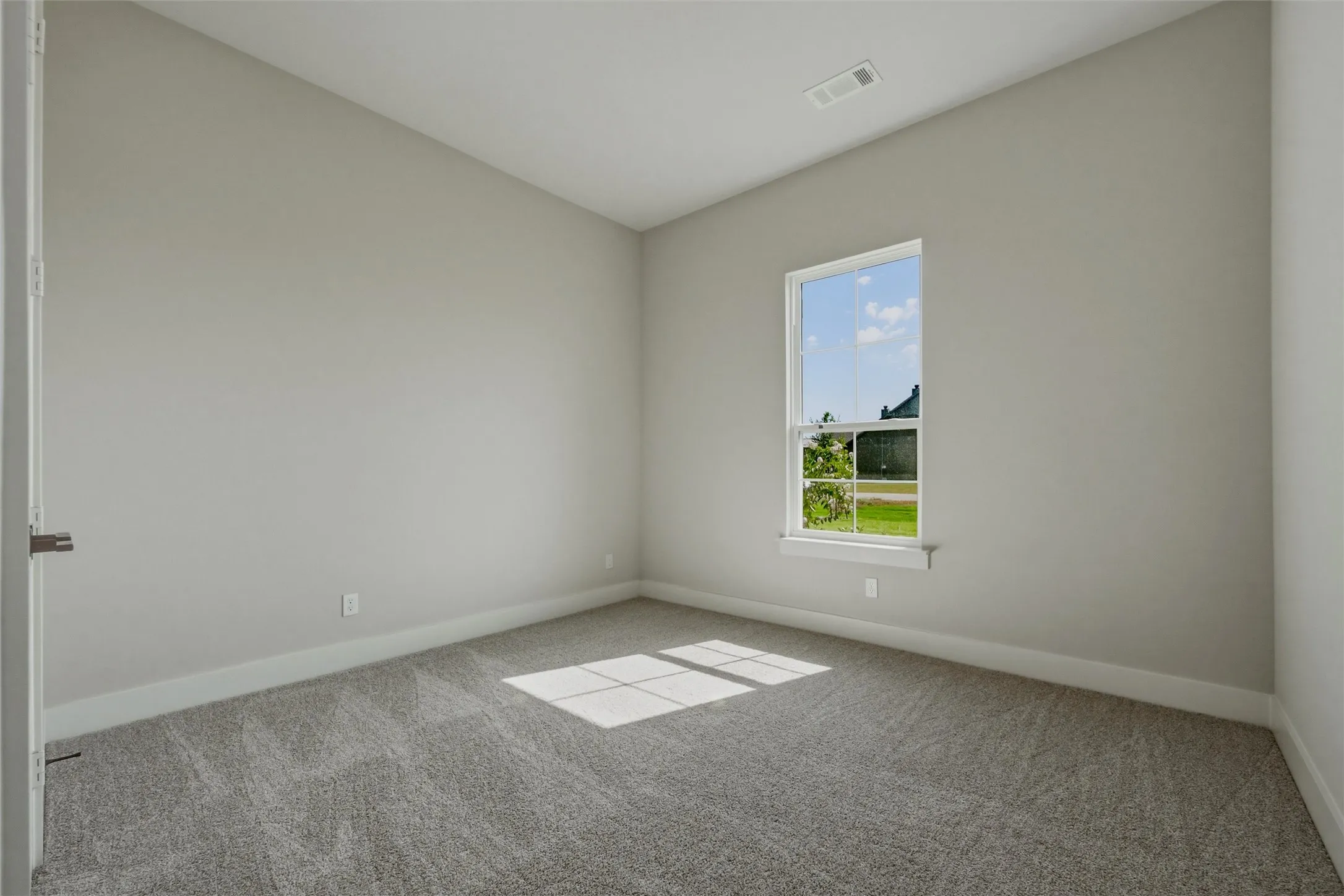 Neutral wall paint, single window, gray carpet flooring, white trim