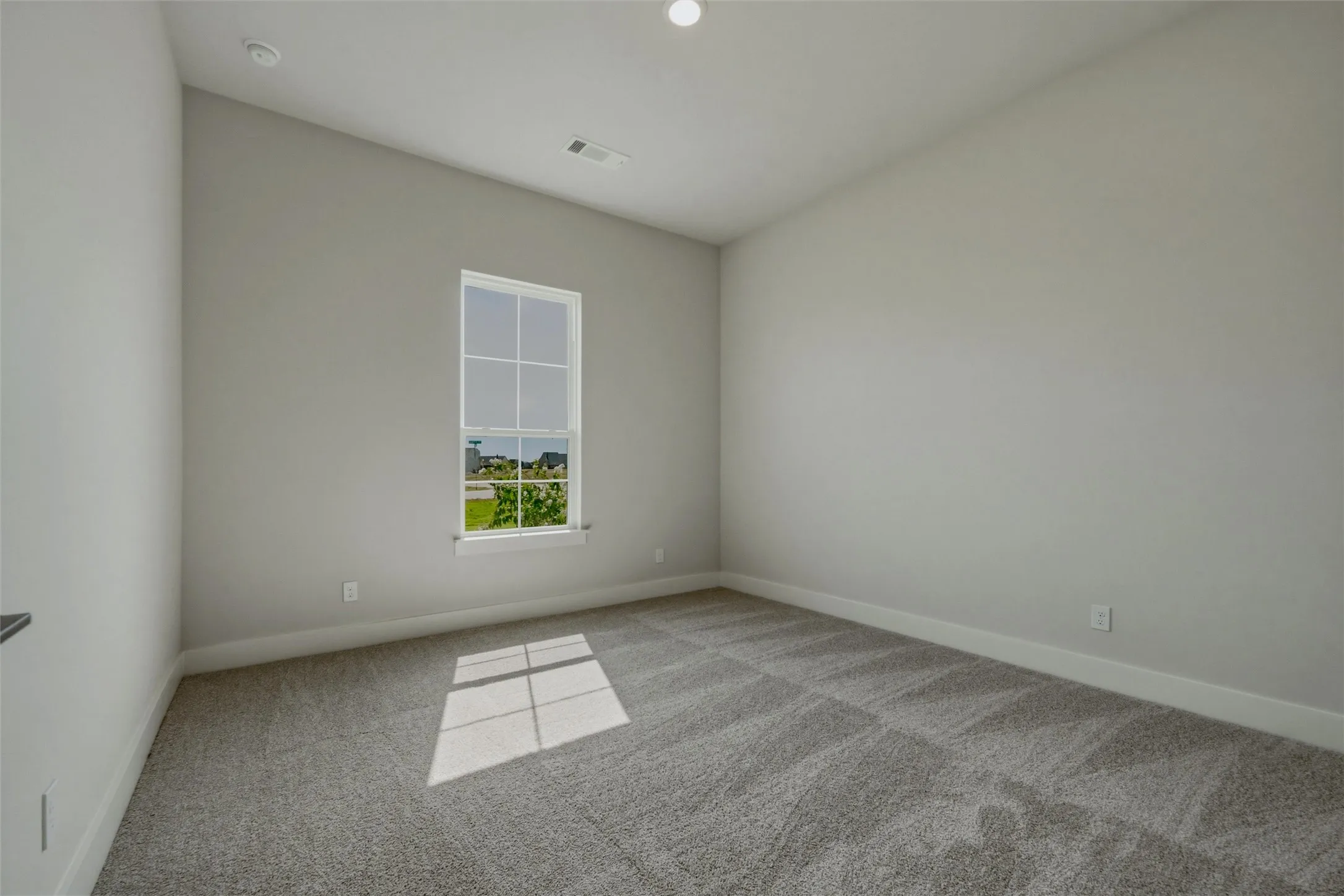 Neutral tone wall paint, vaulted ceiling, recessed lighting, carpet flooring, and a large window