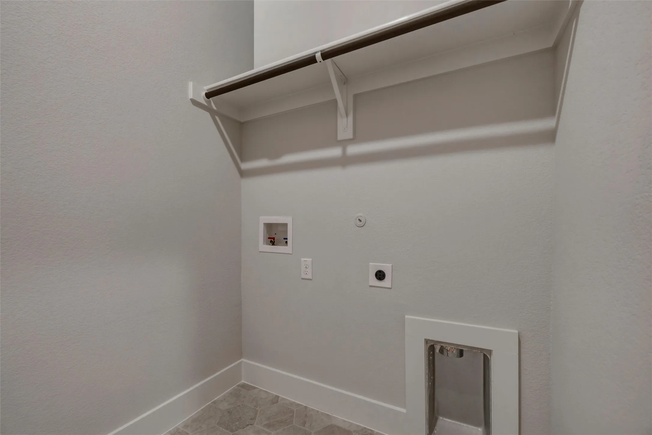 Utility room featuring a built-in shelf, hanging rod, and hexagonal tile flooring