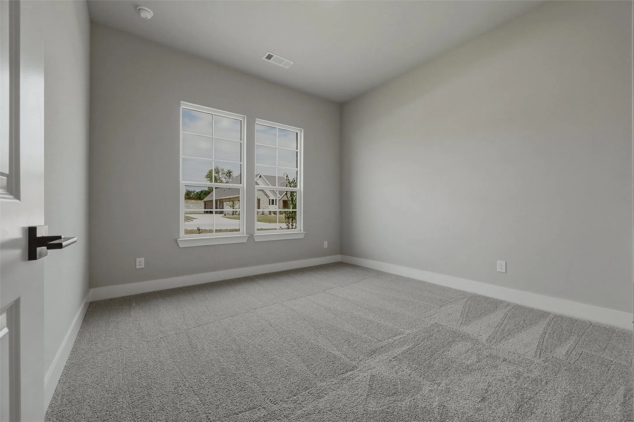 Neutral painted walls with white trim, dual windows, and plush grey carpeting