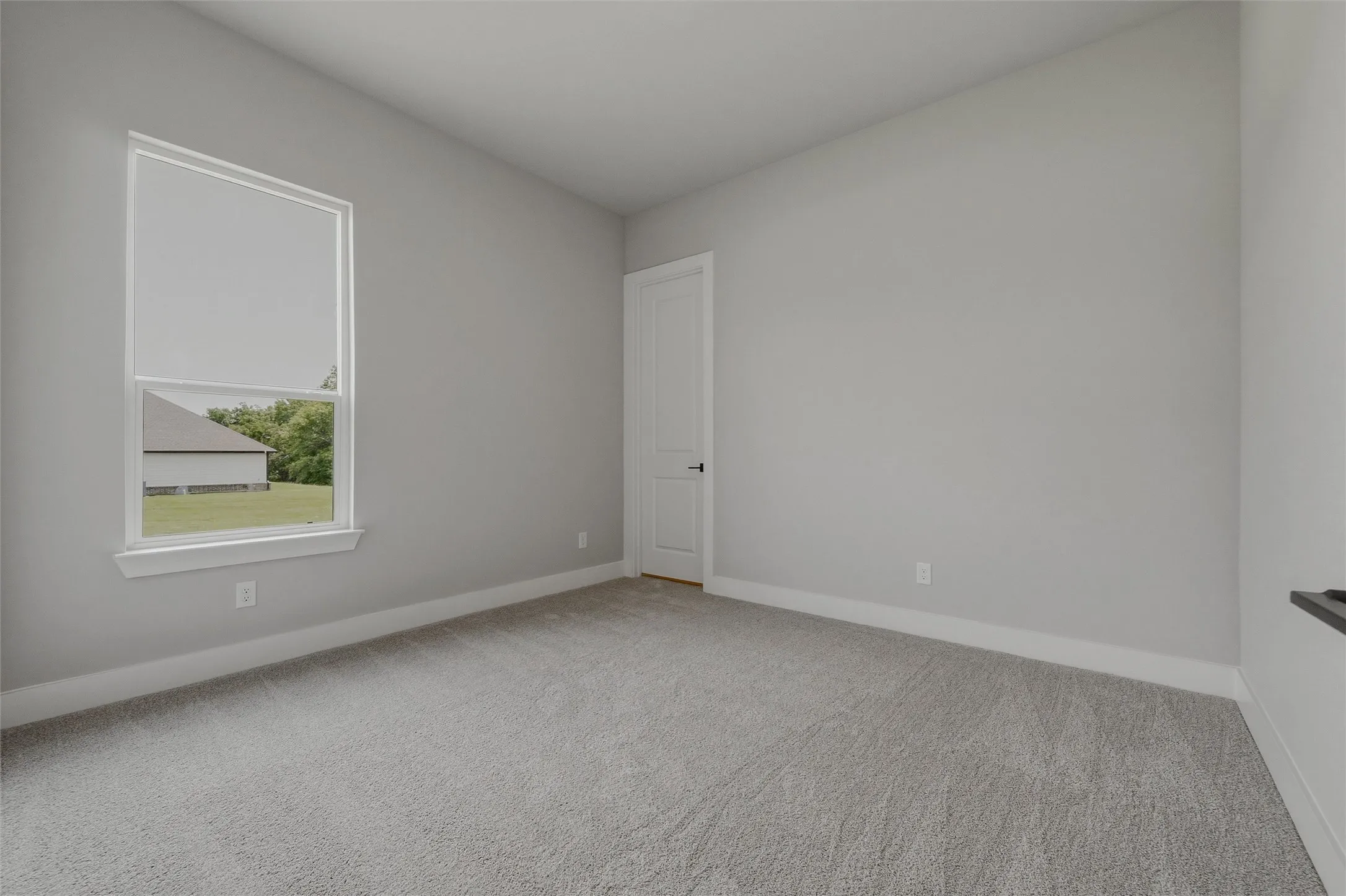 Carpeted flooring, single pane window, neutral wall paint, white trim, and a white interior door