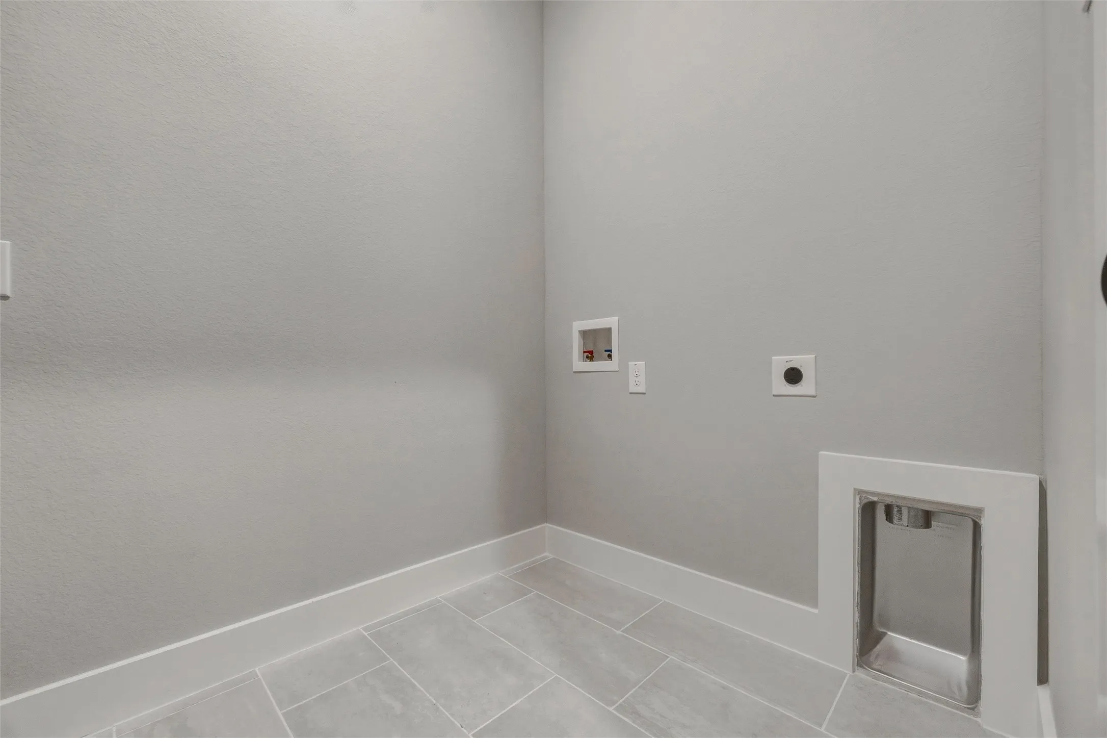 Utility area featuring tile flooring, neutral wall tones, and a built-in laundry sink