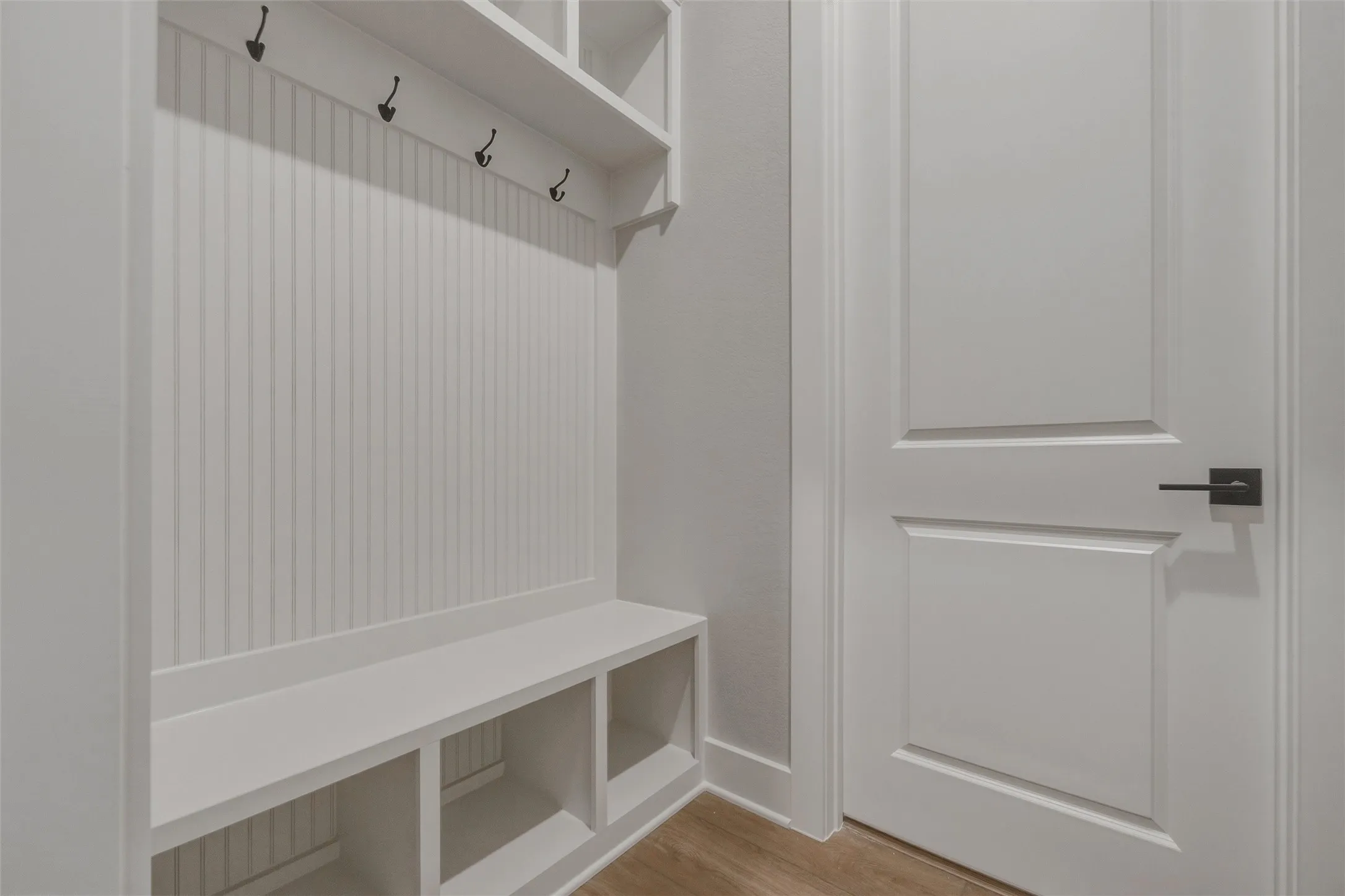Built-in mudroom bench with cubbies, beadboard paneling, and storage hooks
