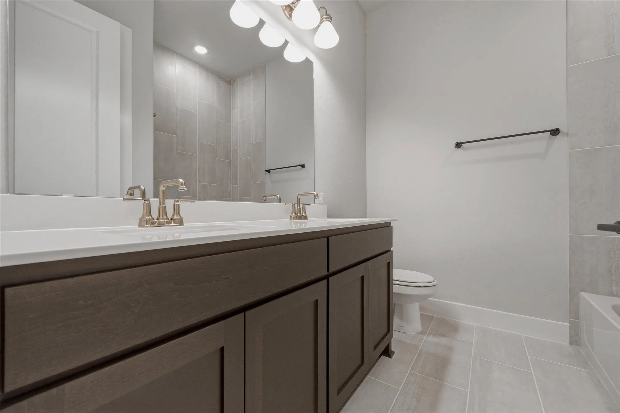 Double vanity with brushed nickel fixtures, dark wood-finish cabinetry, and white countertops