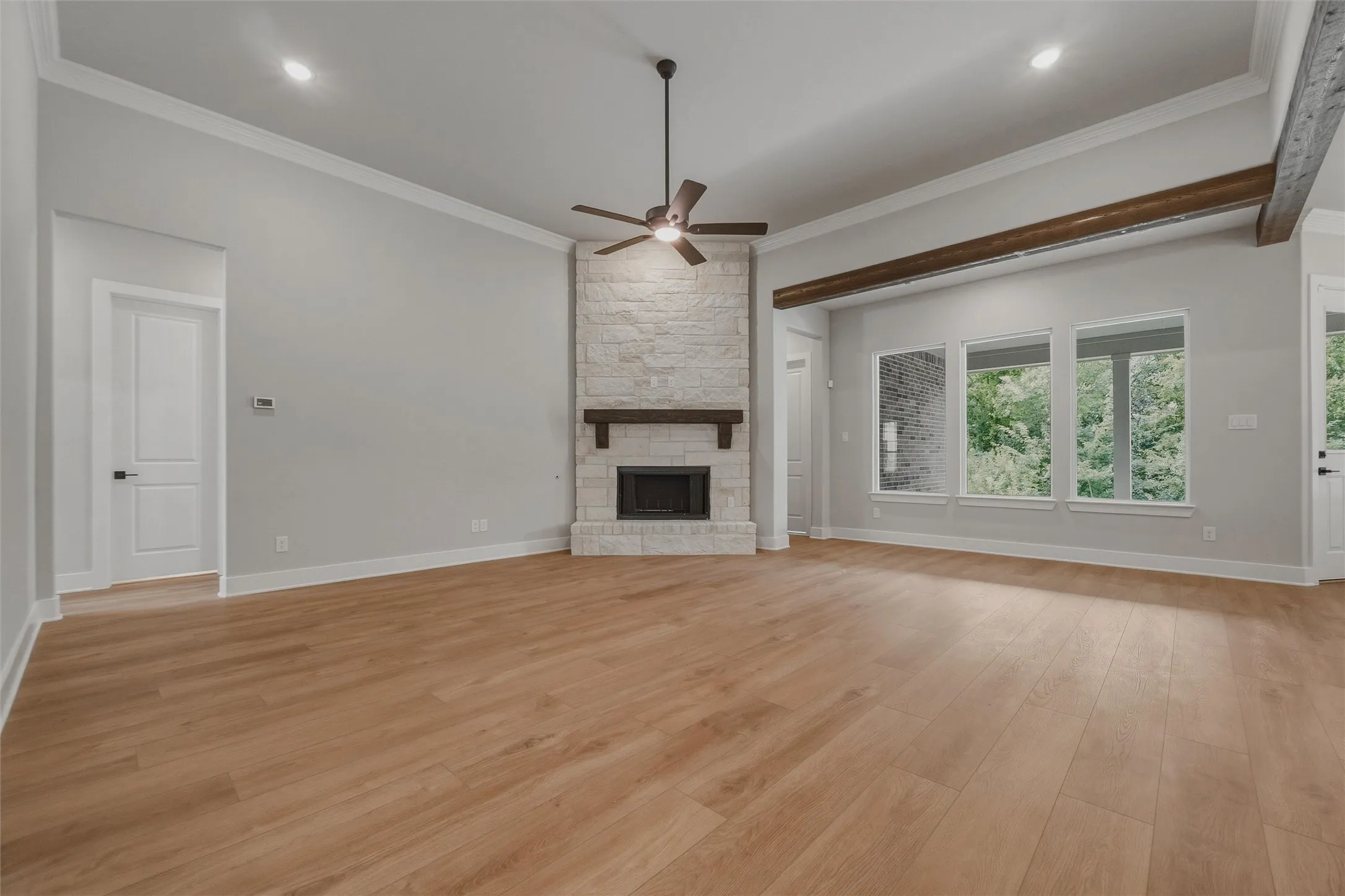 Vaulted ceiling, recessed lighting, wood-finish flooring, stone-clad fireplace, and exposed wood beam accents