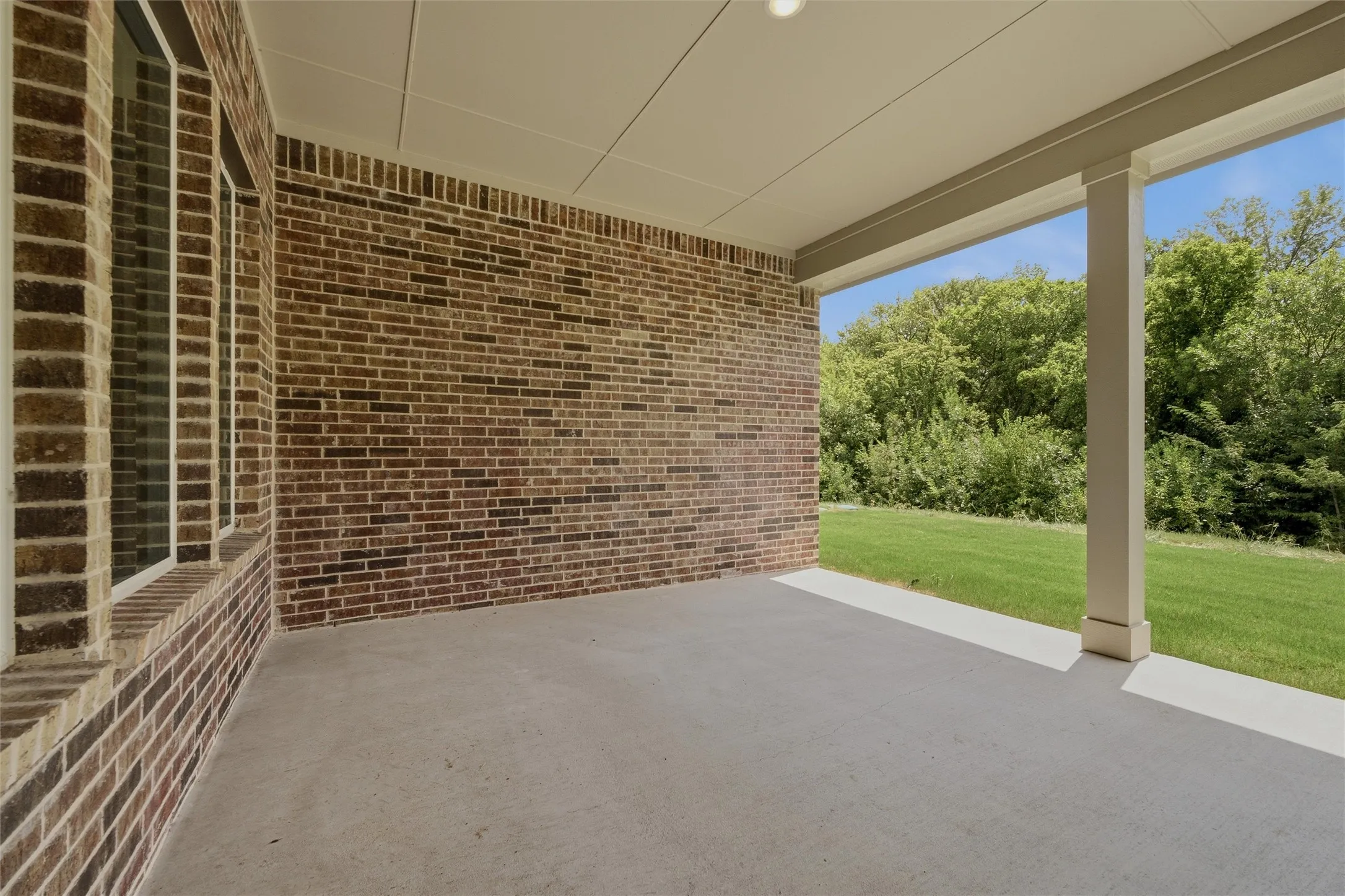 Covered patio featuring a concrete surface, brick exterior wall, and integrated ceiling light