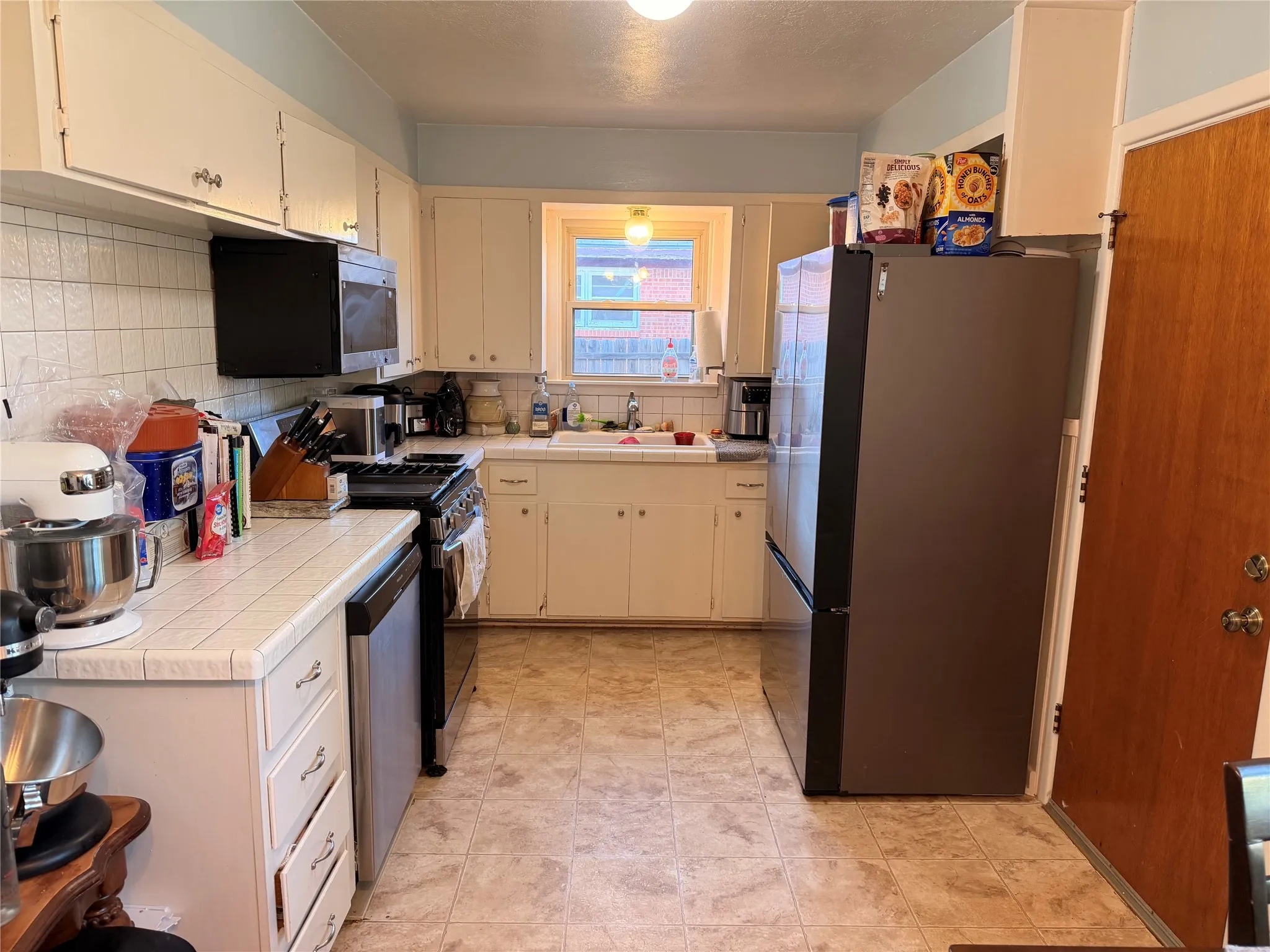 Galley kitchen featuring white cabinetry, a tiled backsplash, and wood-finish flooring