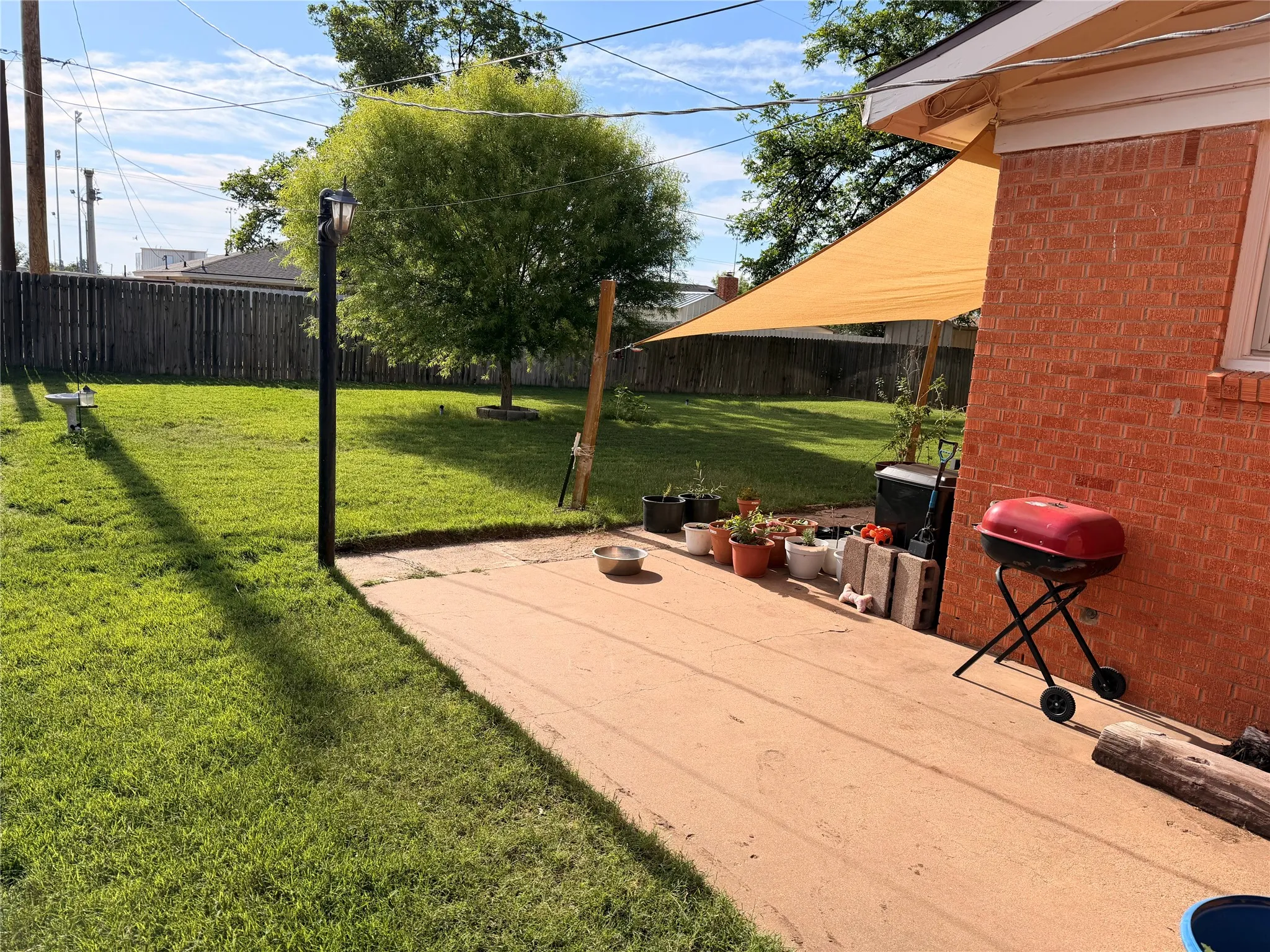 Expansive backyard featuring a concrete patio, mature trees, and a privacy fence