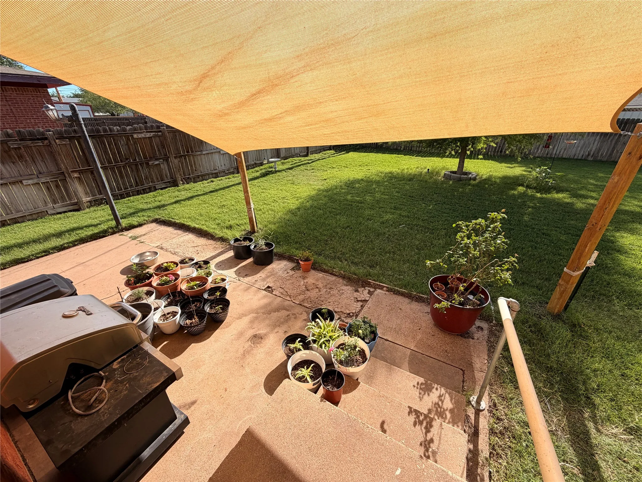 Patio area featuring a concrete surface, a partial shade structure, and a metal handrail