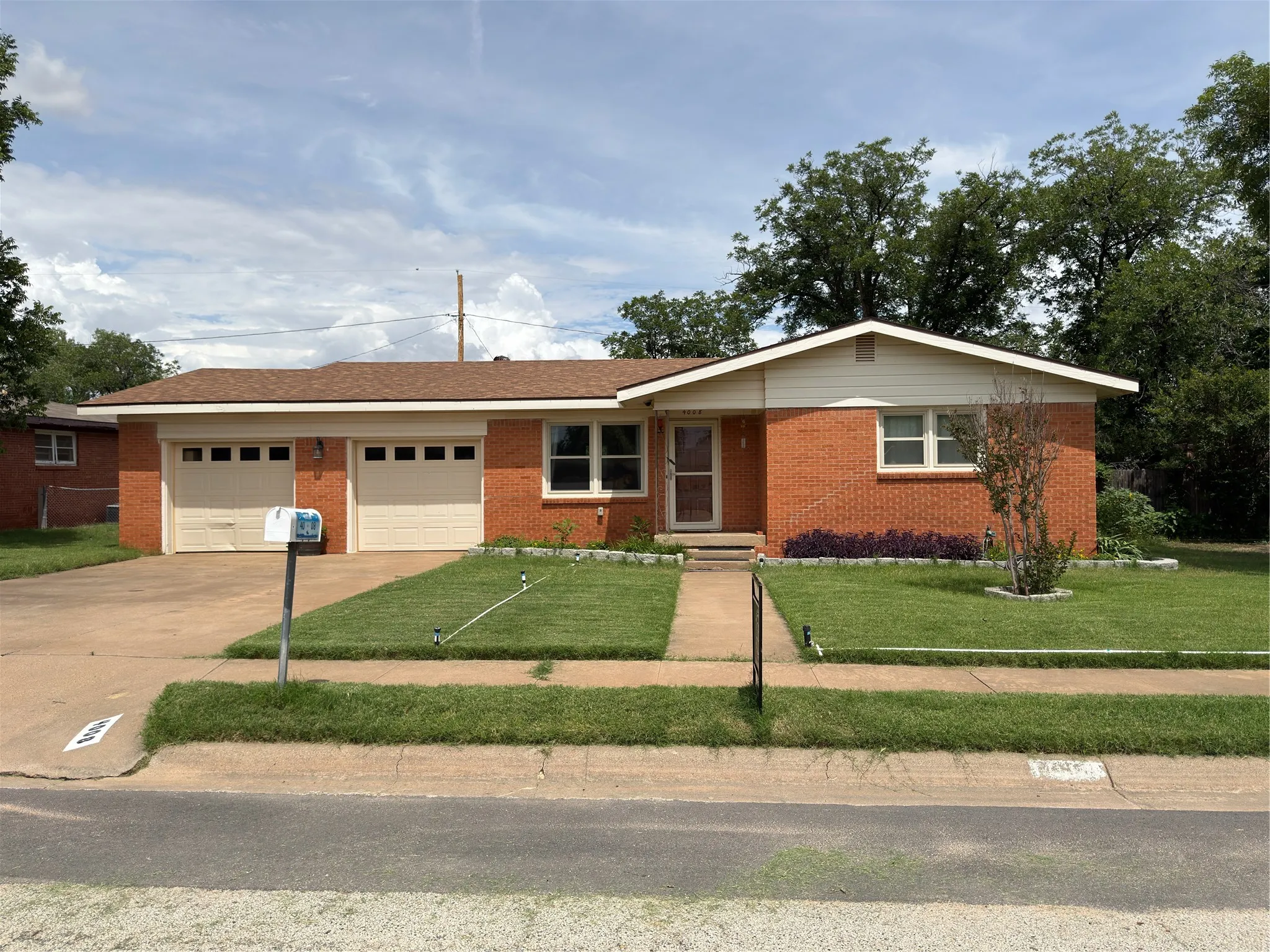 Brick exterior home featuring a two-car garage, concrete driveway, and front walk