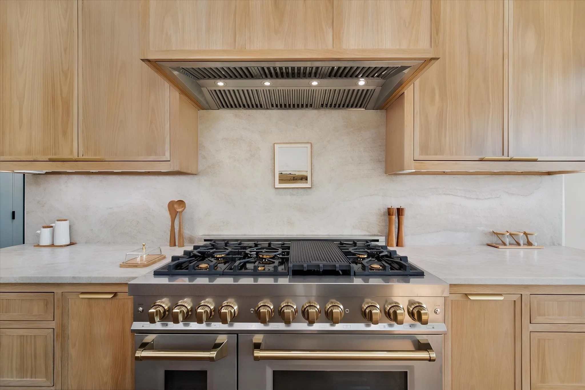 Commercial-grade gas range and oversized vent hood create an impressive cooking station.