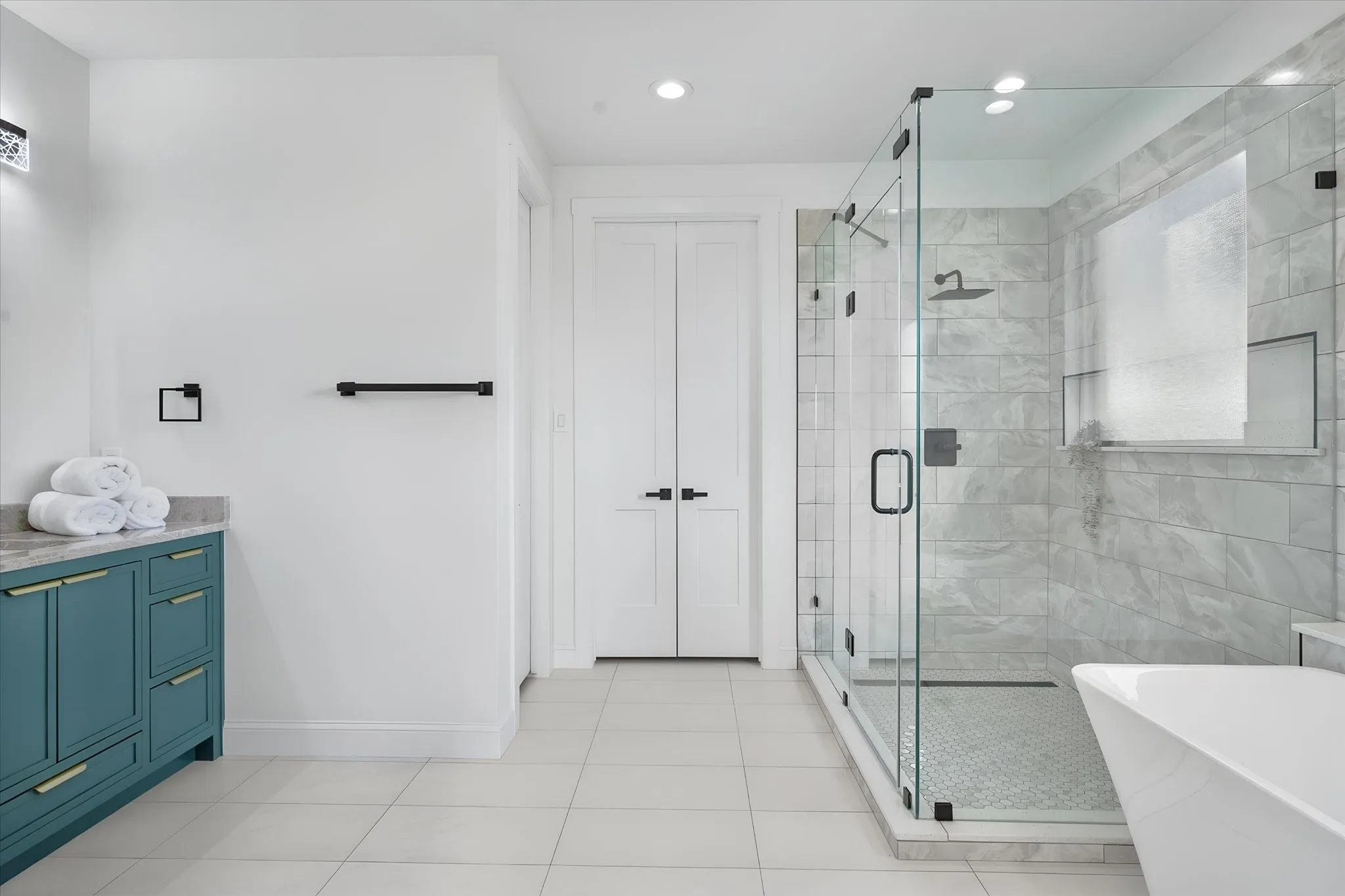 Spacious primary bathroom includes a frameless glass shower and sophisticated tile finishes.