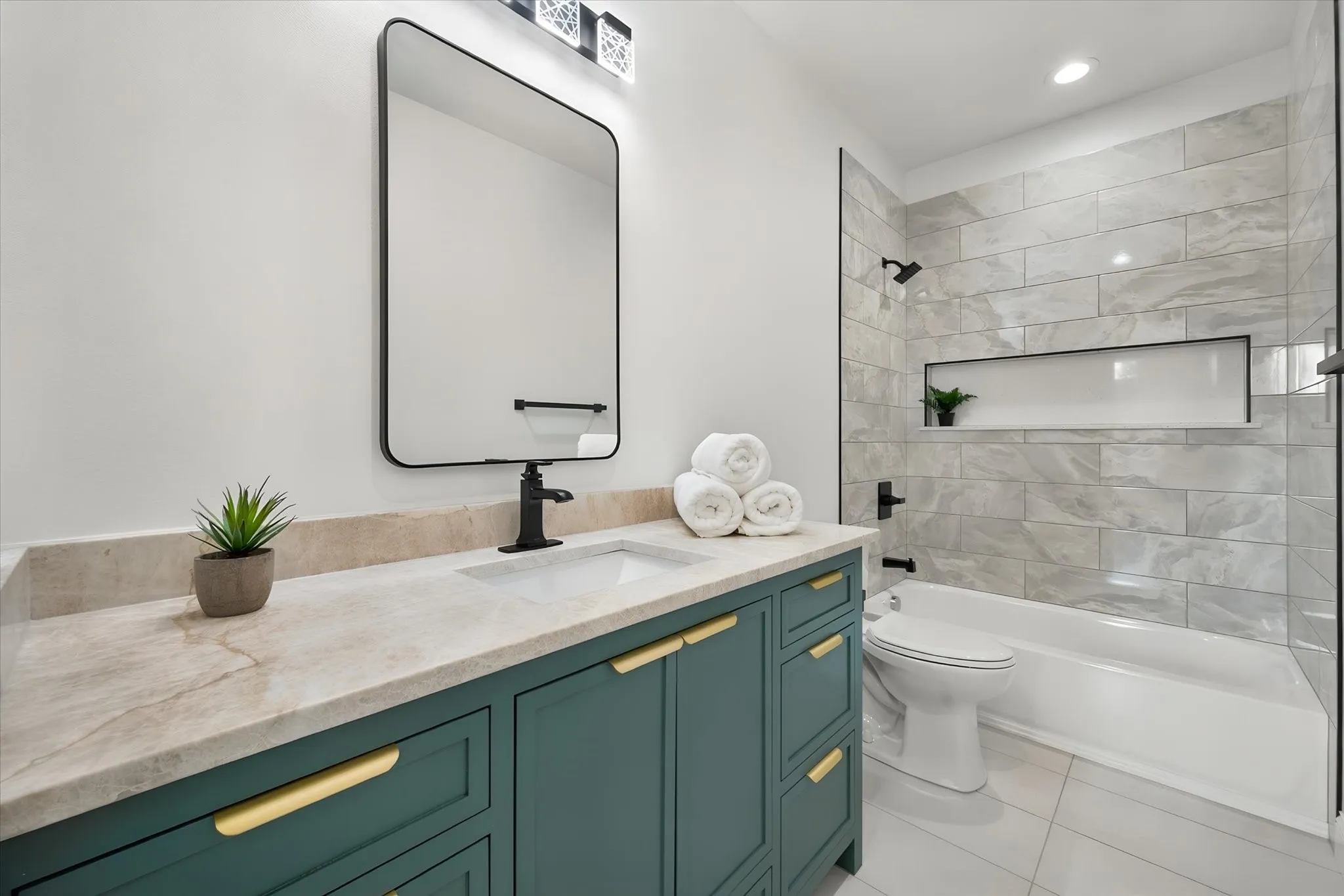 Well-appointed full bathroom combines rich vanity cabinetry with a tiled tub and shower surround.