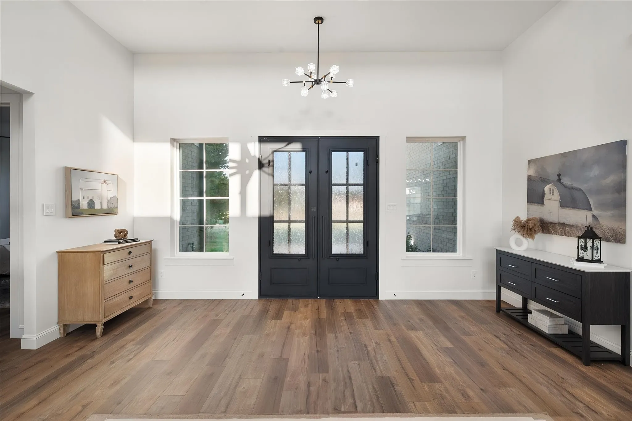 Bright, welcoming entry with double front doors, warm wood-look flooring, and modern finishes.