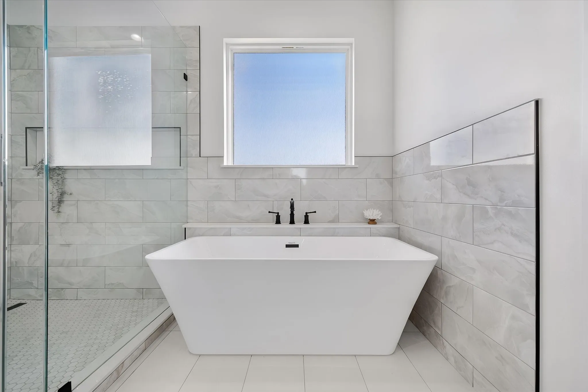 Spa-inspired primary bath pairs a freestanding tub with a large tiled shower and abundant natural light.