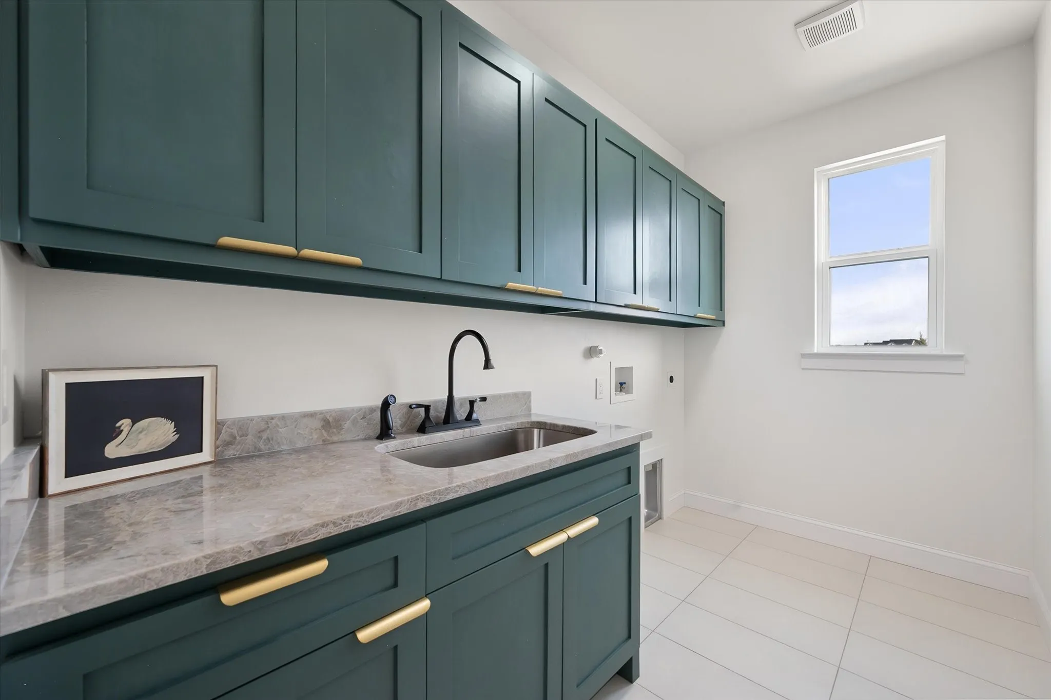 Dedicated laundry room offers extensive cabinetry, countertop workspace, and a utility sink.