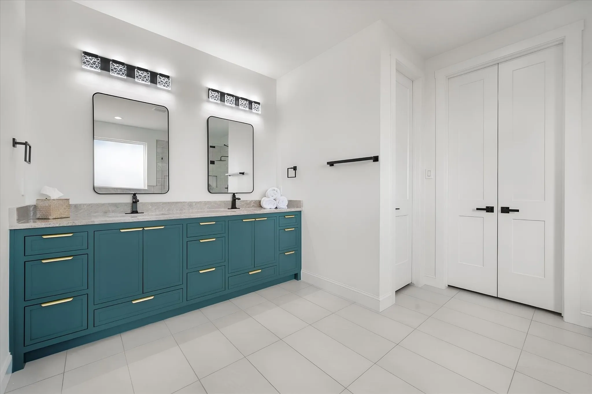 Primary bath features a long dual-sink vanity with rich cabinetry and contemporary fixtures.