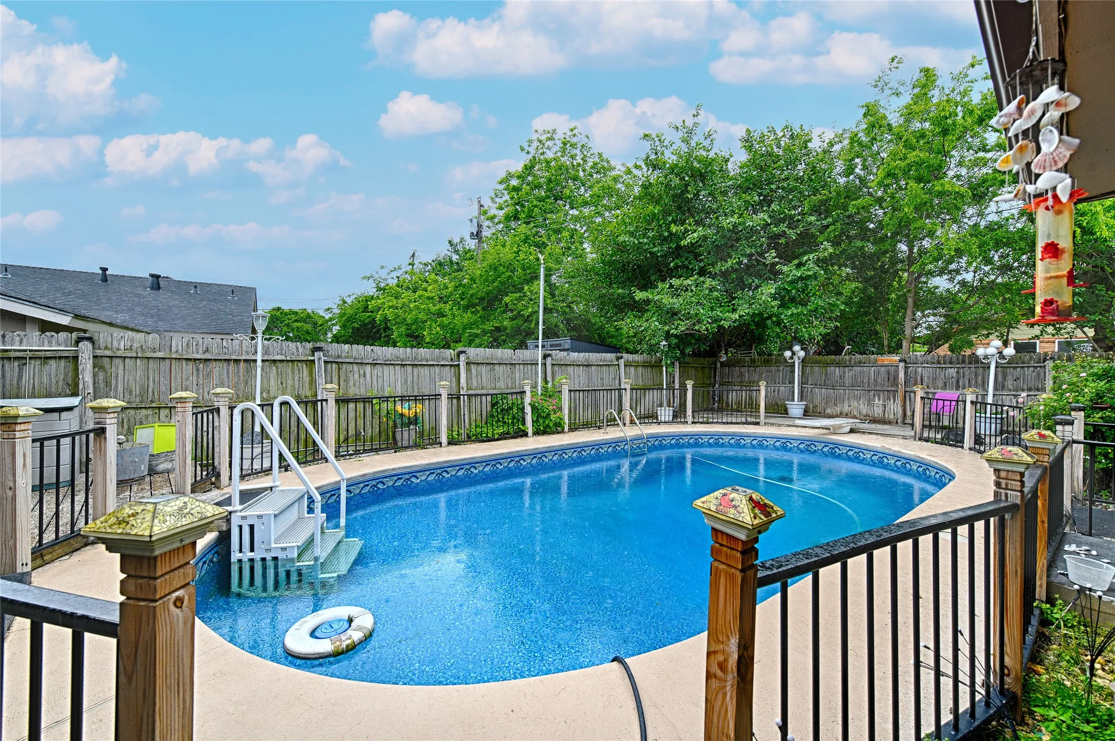 In-ground swimming pool with an integrated deck, safety railings, and a privacy fence