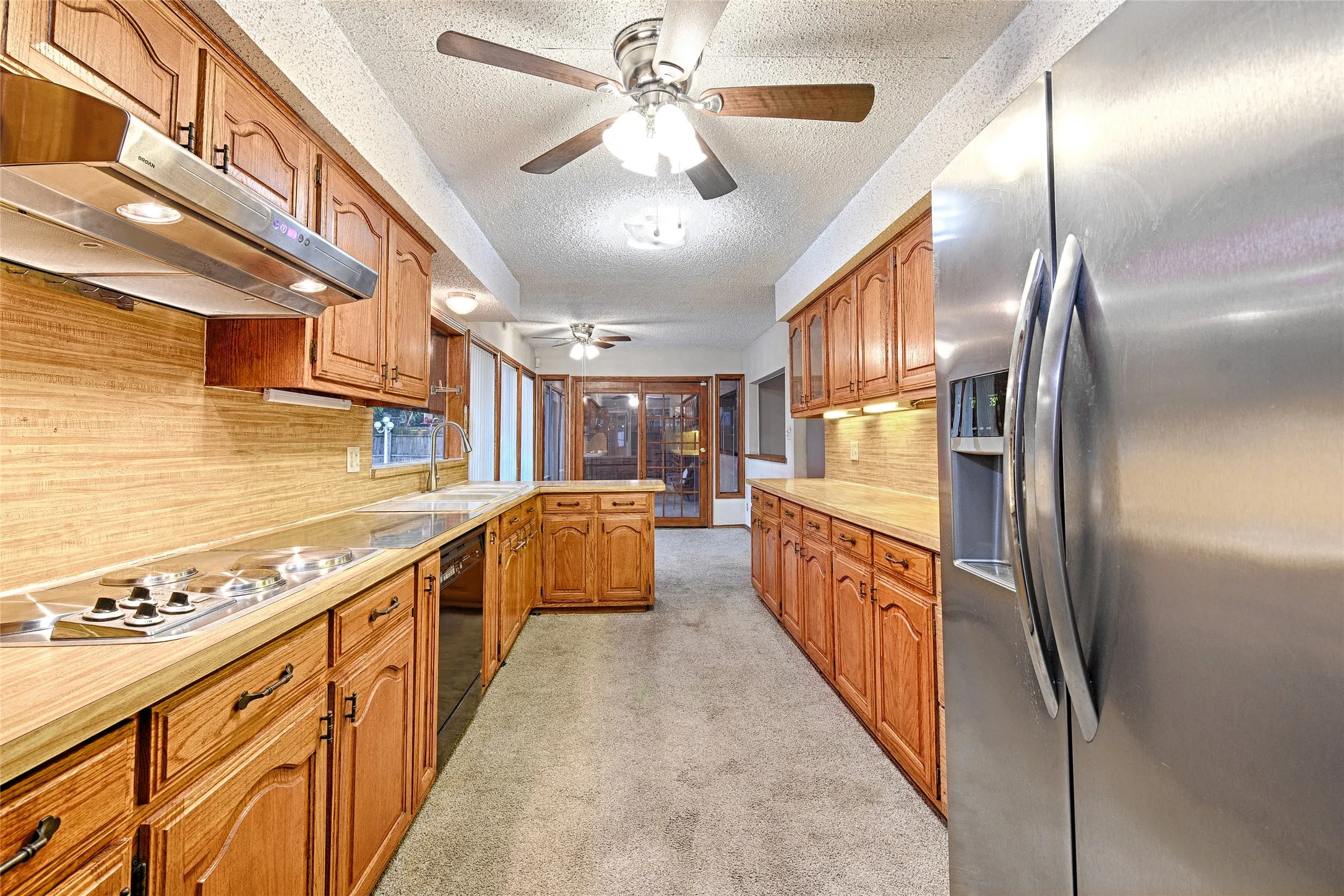 Kitchen featuring light wood cabinetry, a built-in gas cooktop, stainless steel refrigerator, and ample counter space