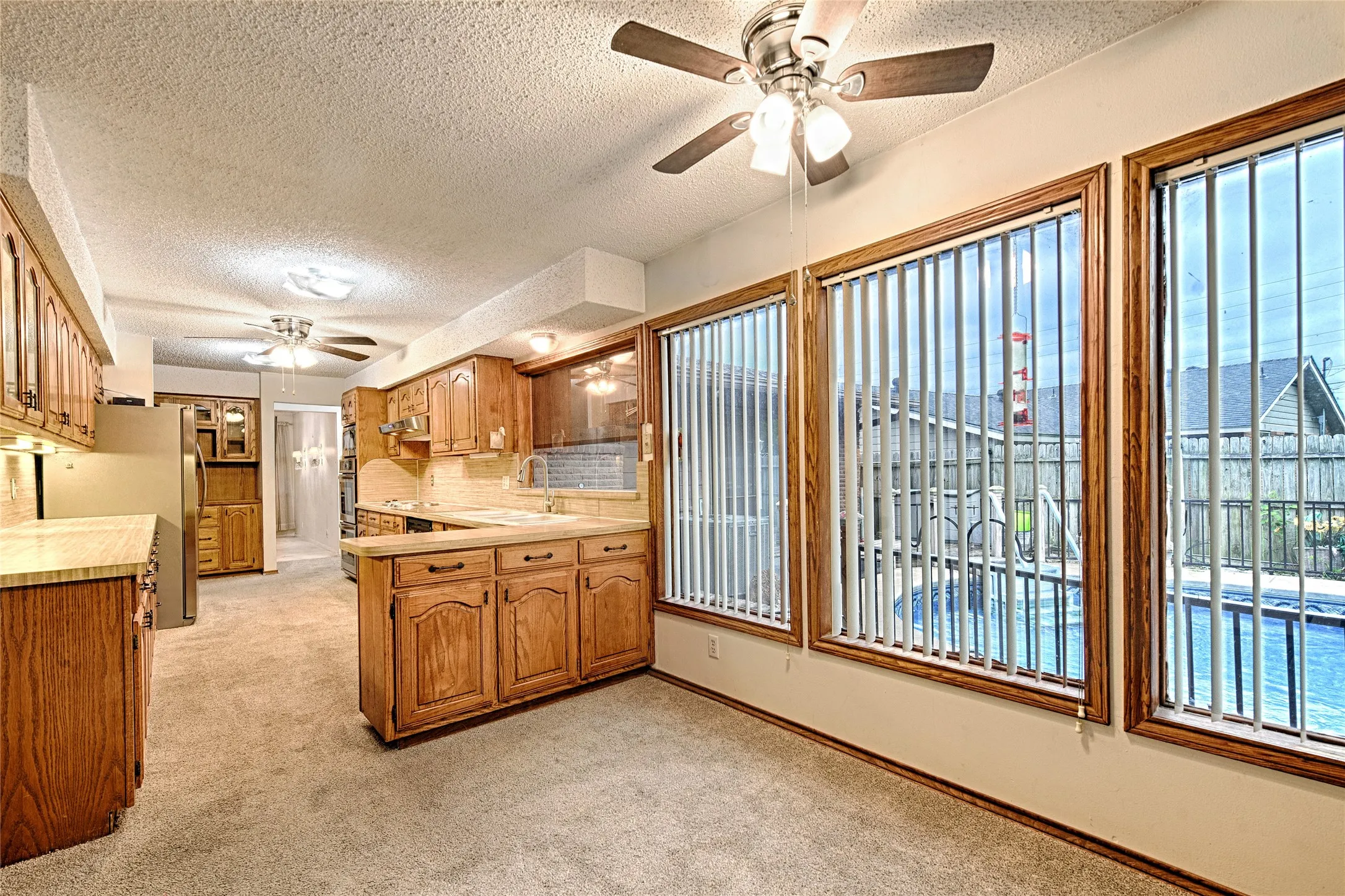 Kitchen area featuring wood-finish cabinetry, light-toned countertops, and carpet flooring