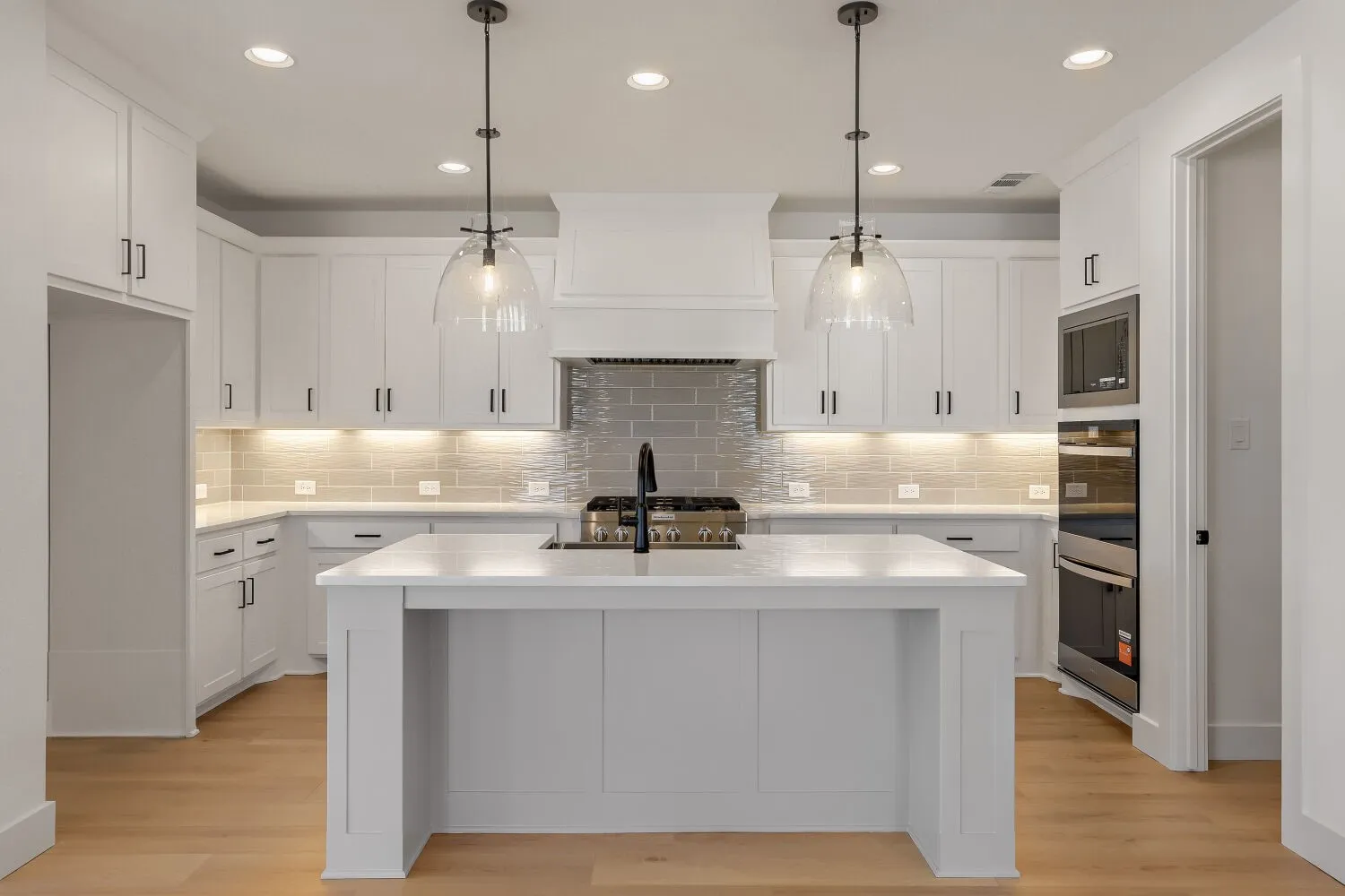 Modern kitchen featuring white cabinetry, a central island, stainless steel appliances, pendant lighting, and light wood-finish flooring