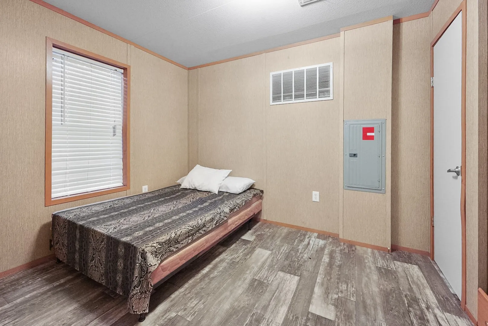 Bedroom featuring wood-finish flooring, a window with blinds, and light-toned wall paneling