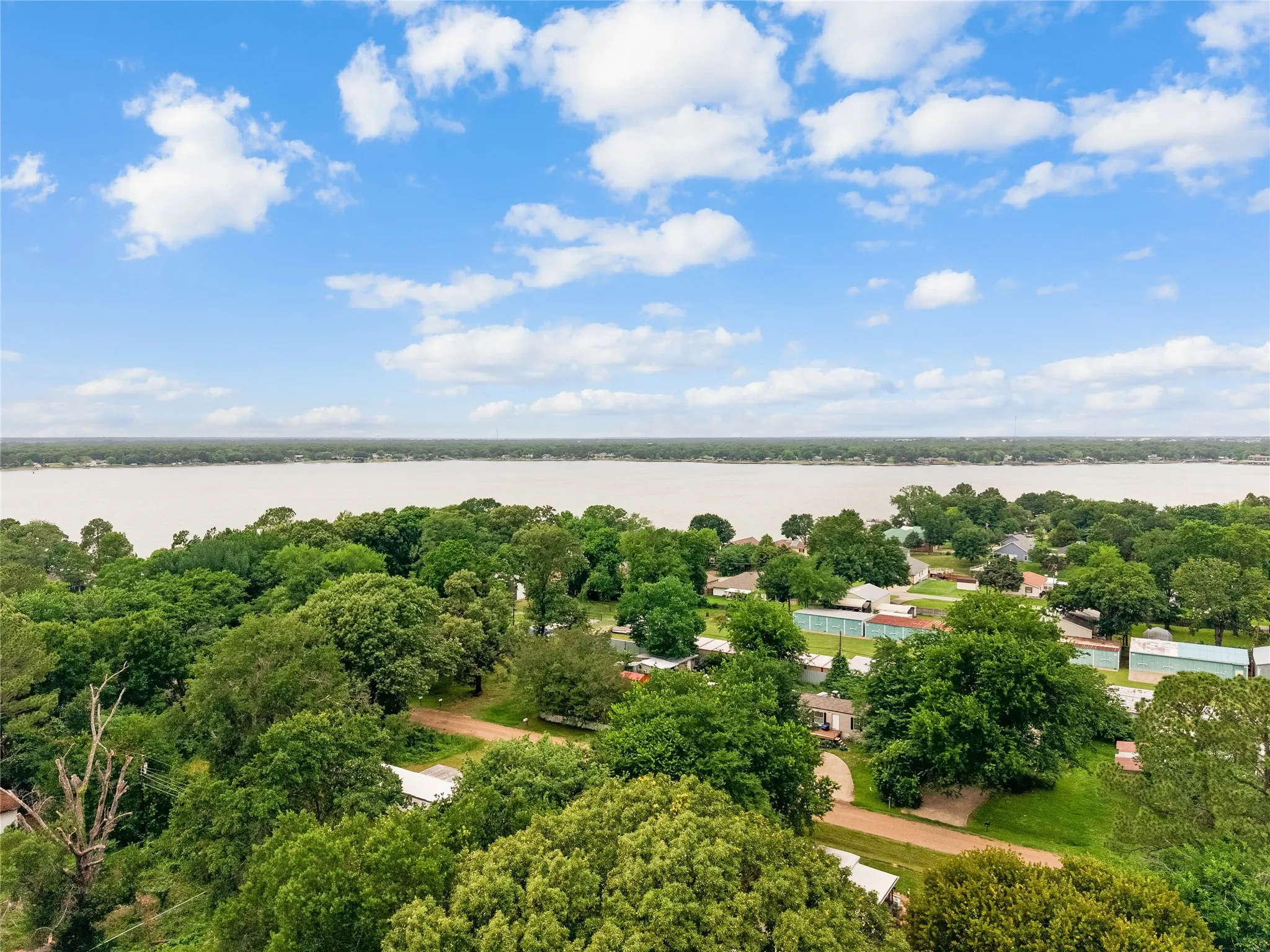 Expansive waterfront property featuring mature trees and a scenic water backdrop