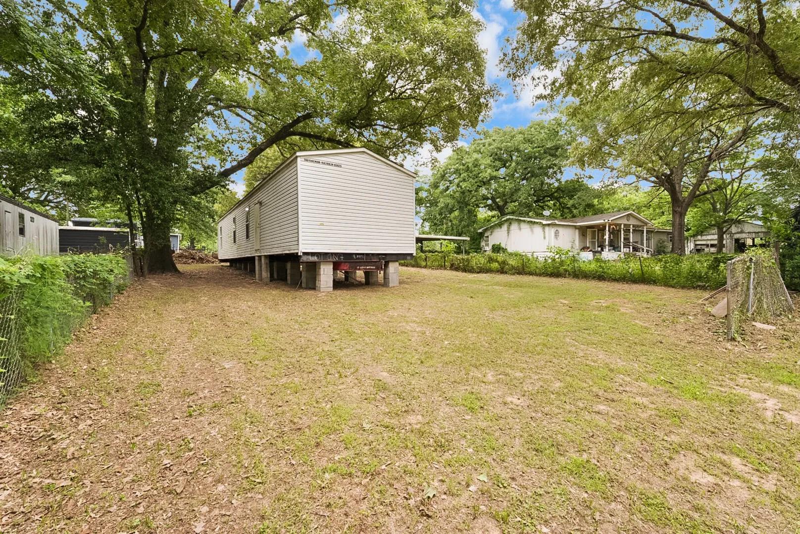 Expansive lawn area featuring mature trees and a chain-link fence