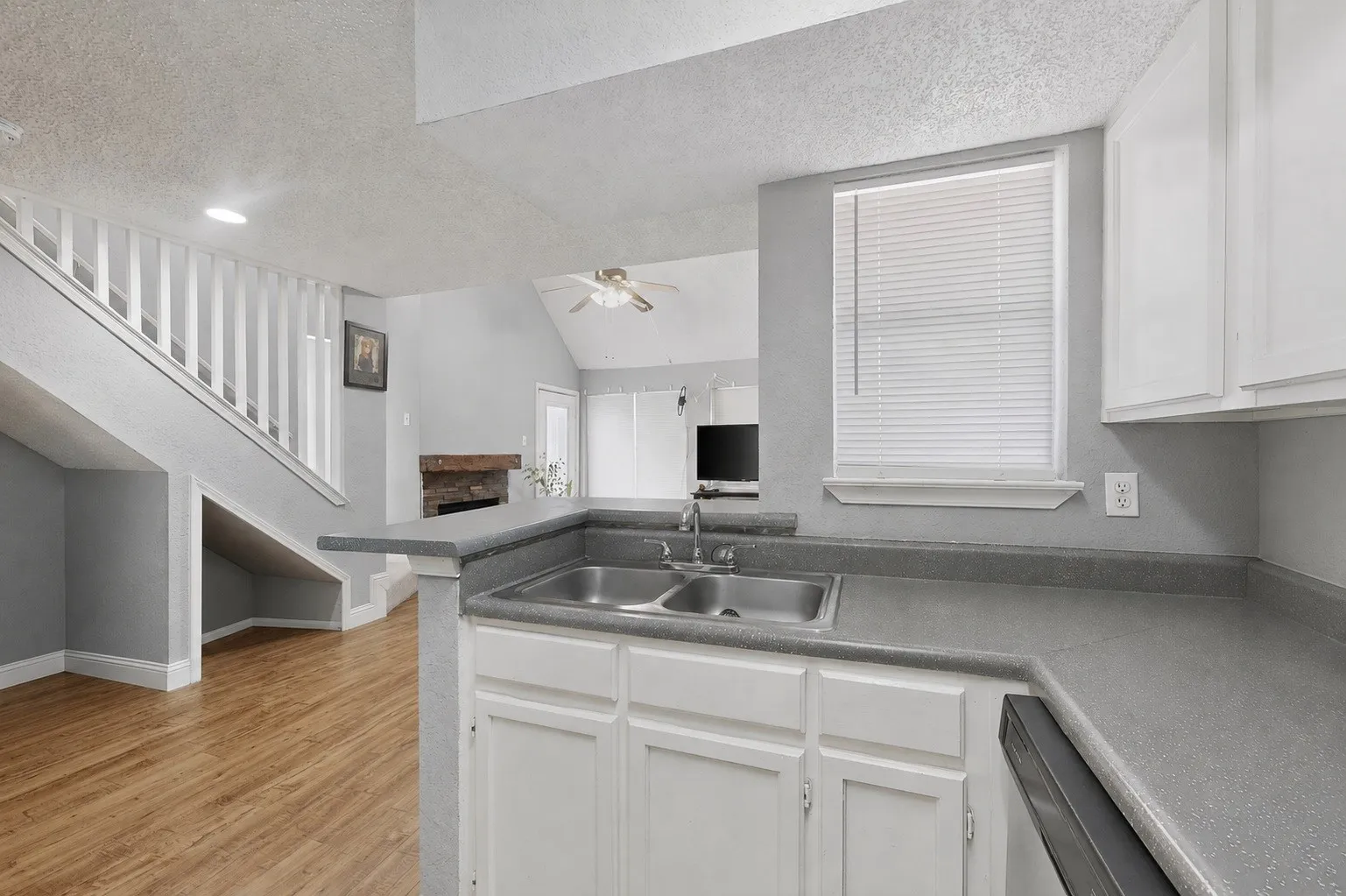 Kitchen featuring a dual basin sink, gray countertops, and white cabinetry