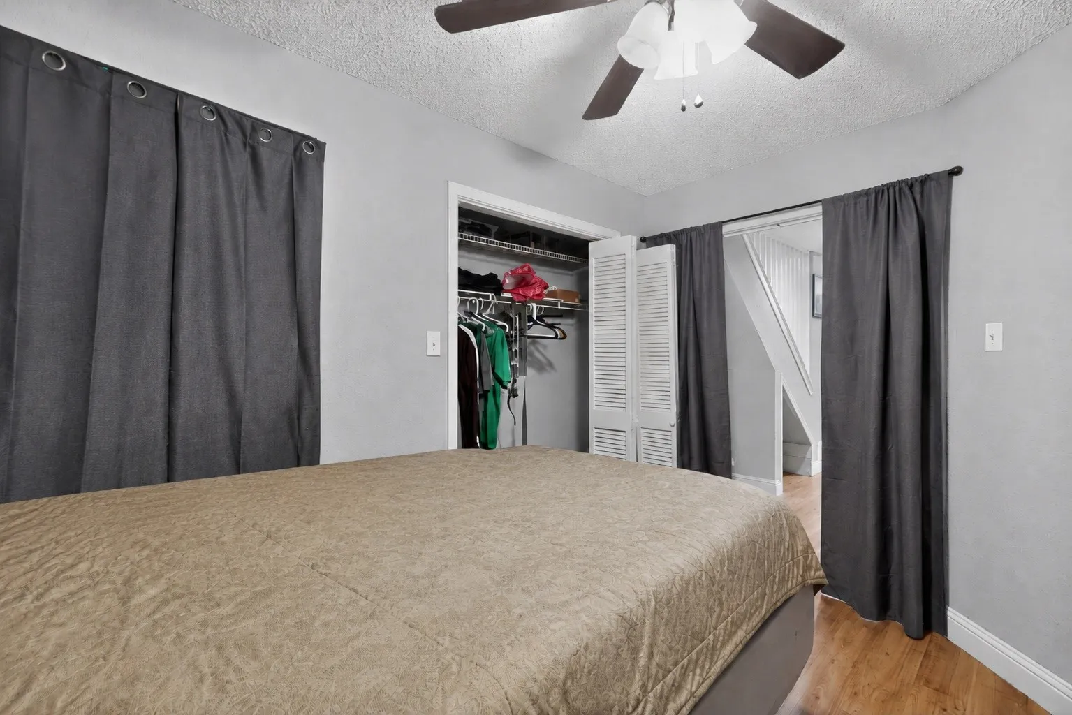 Bedroom featuring wood-finish flooring, a ceiling fan with integrated lighting, and light gray wall finishes