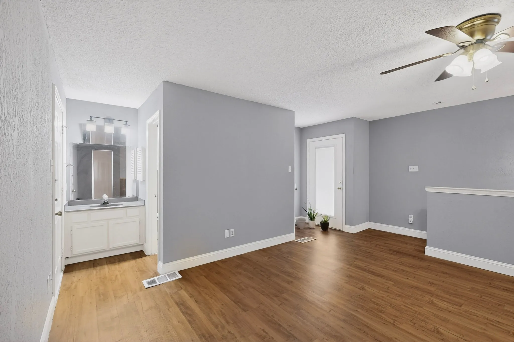 Spacious room featuring wood-finish flooring, light gray walls, and white trim