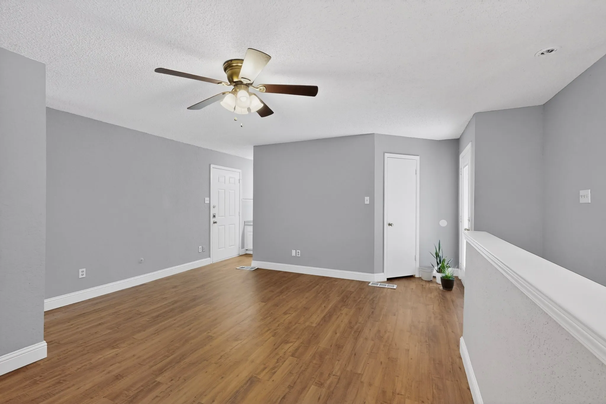 Spacious interior featuring wood-finish flooring, light gray walls, and white baseboards