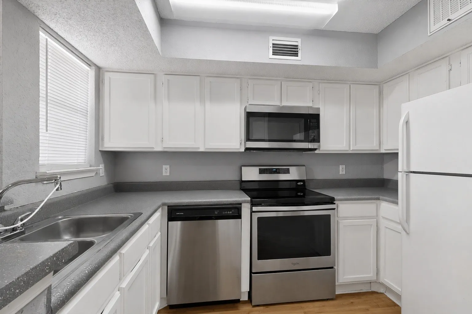 Kitchen featuring white cabinetry, grey countertops, a stainless steel microwave, and a stainless steel range