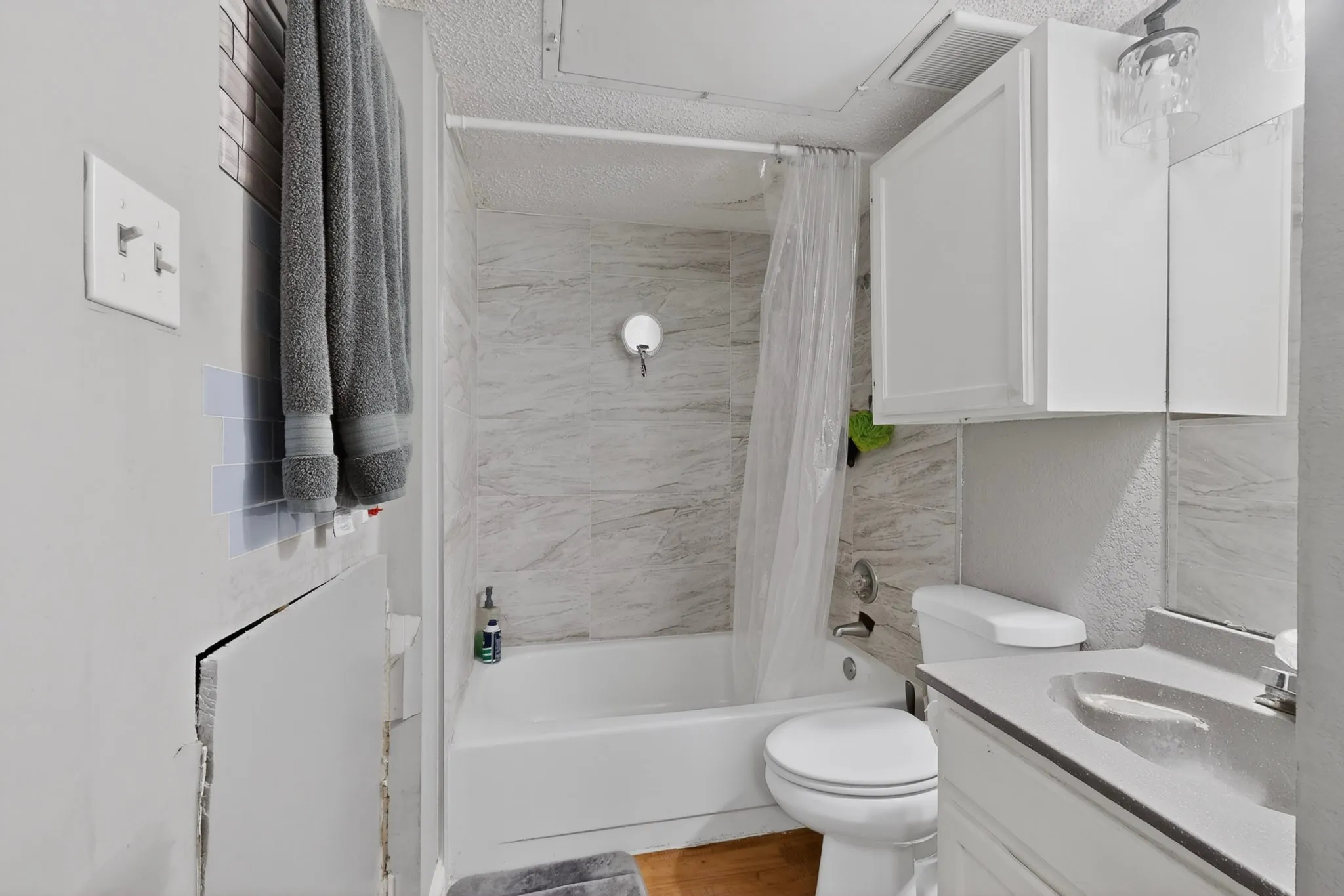 Bathroom featuring a white bathtub with a tiled shower surround, a white toilet, and a vanity with an integrated sink and white cabinetry