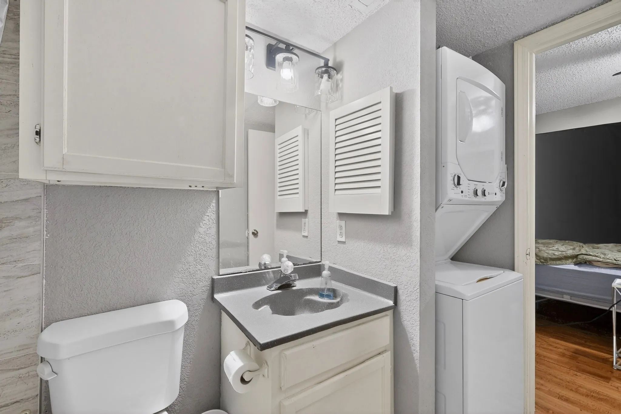 Bathroom featuring a single vanity with a dark countertop and white cabinetry, a mirror, and overhead lighting