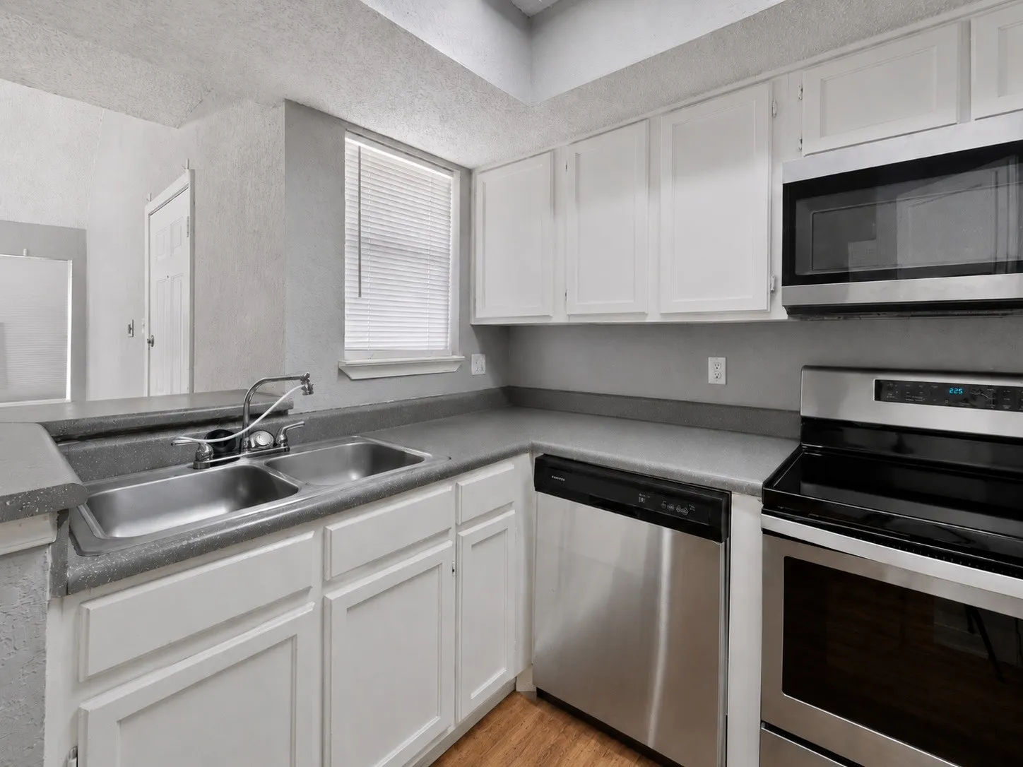 Kitchen featuring a double stainless steel sink, white cabinetry, and stainless steel appliances