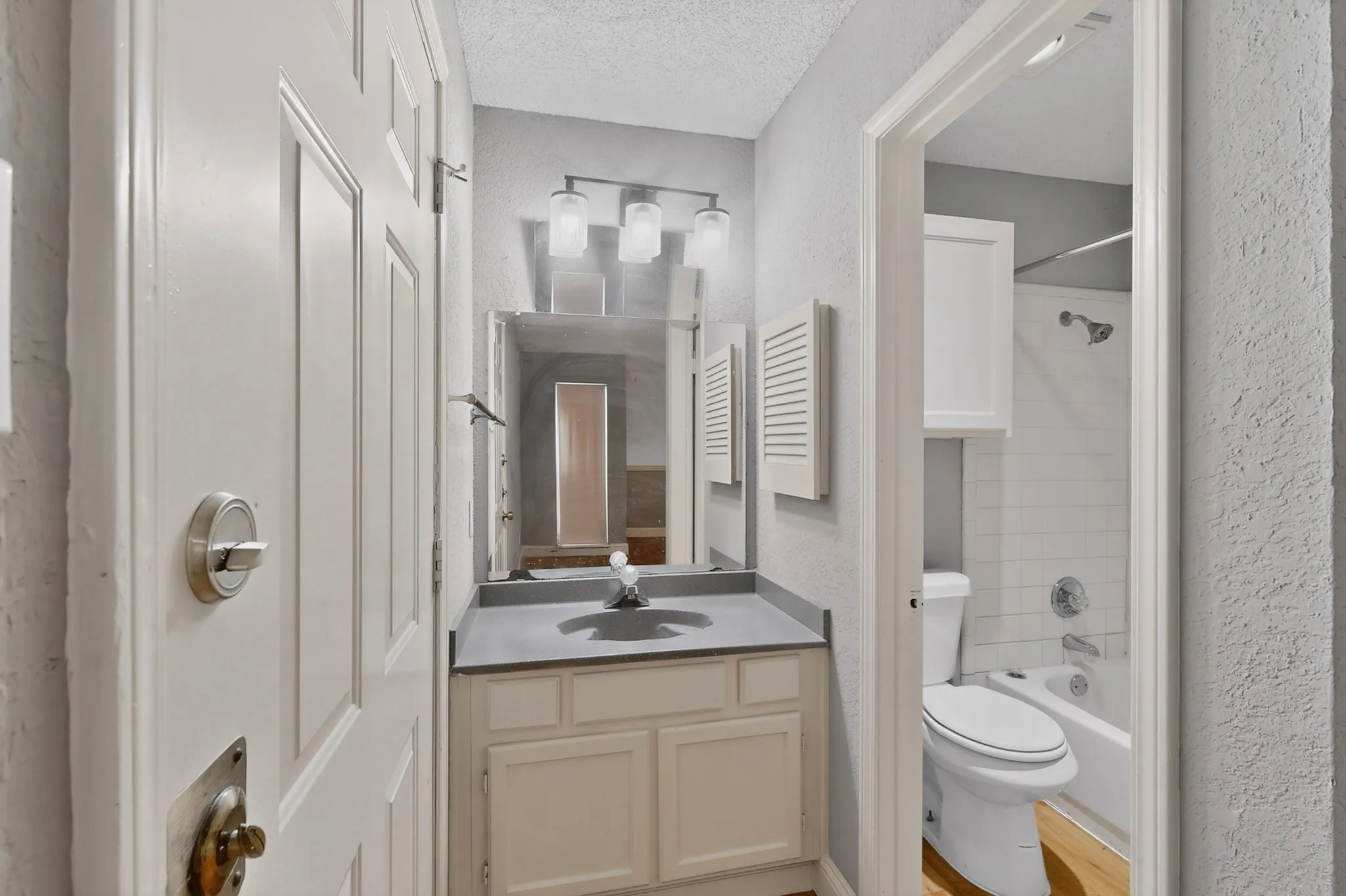 Bathroom vanity featuring a single basin, grey countertop, and a white cabinet with dual doors