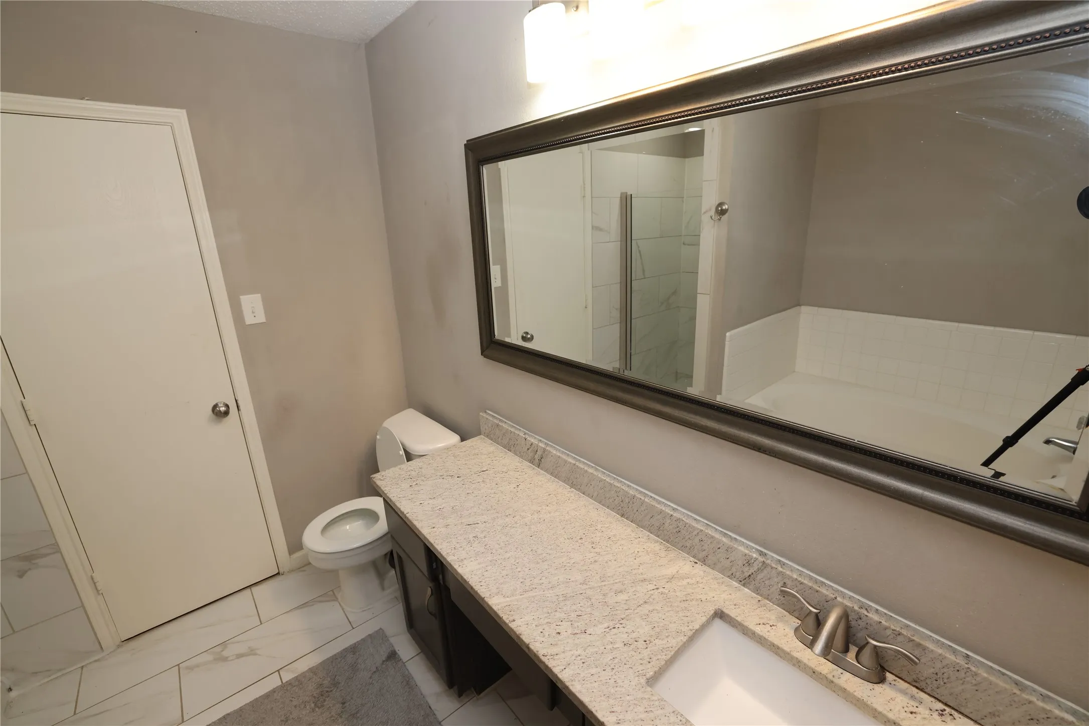 Bathroom featuring an expansive vanity with a stone-finish countertop, dual-basin sink, and brushed nickel fixtures