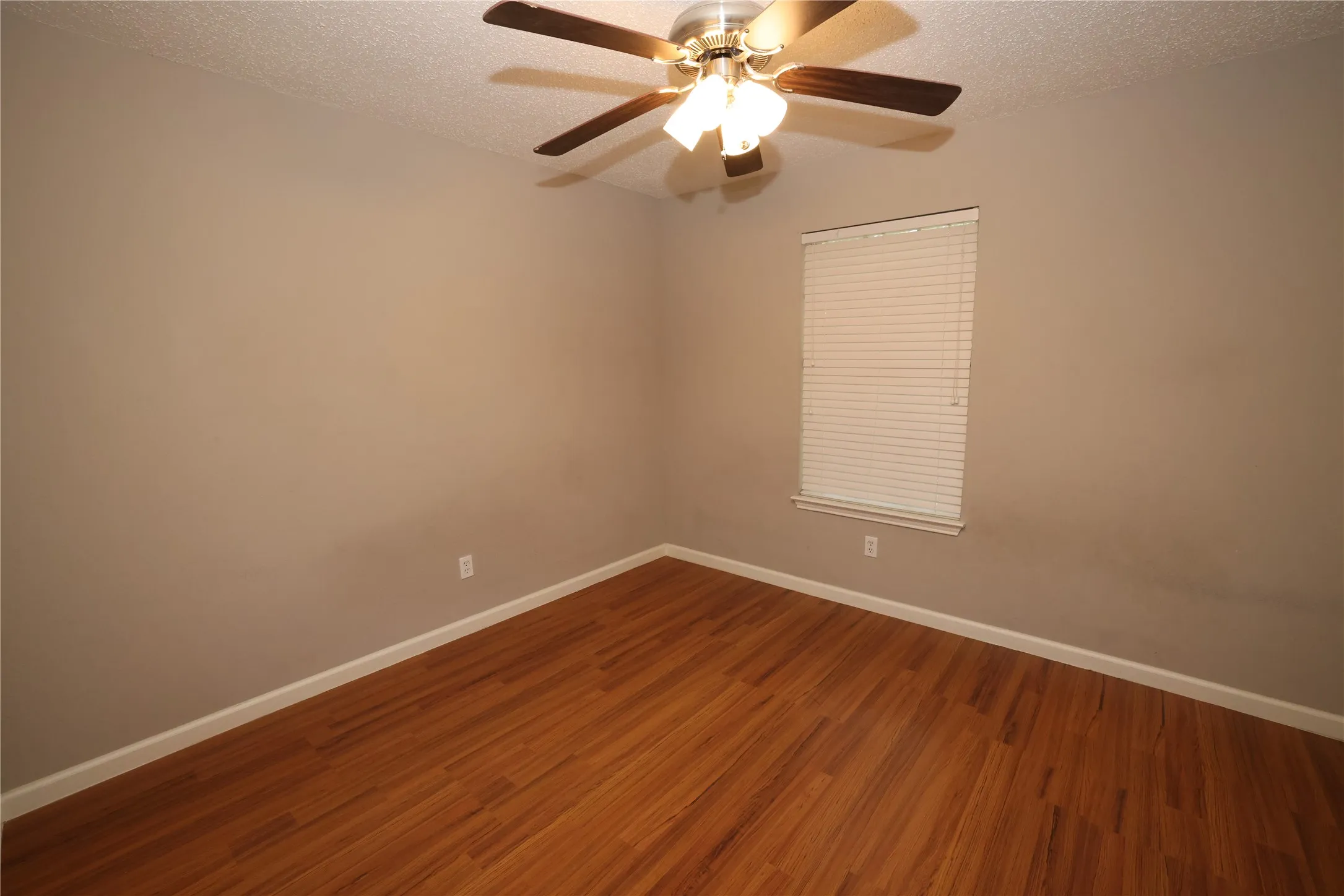 Room featuring wood-finish flooring, a window with blinds, a ceiling fan with integrated lighting, and neutral-toned walls