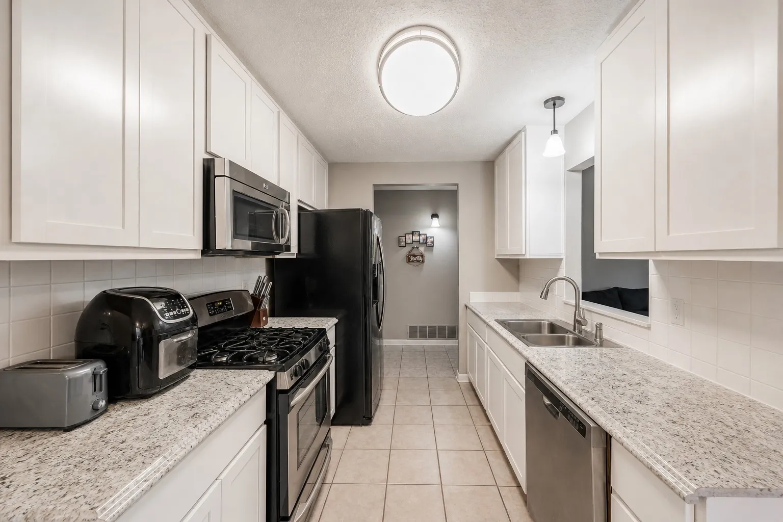 Kitchen features stainless steel gas range, microwave and a tiled backsplash. Photo has been digitally enhanced.