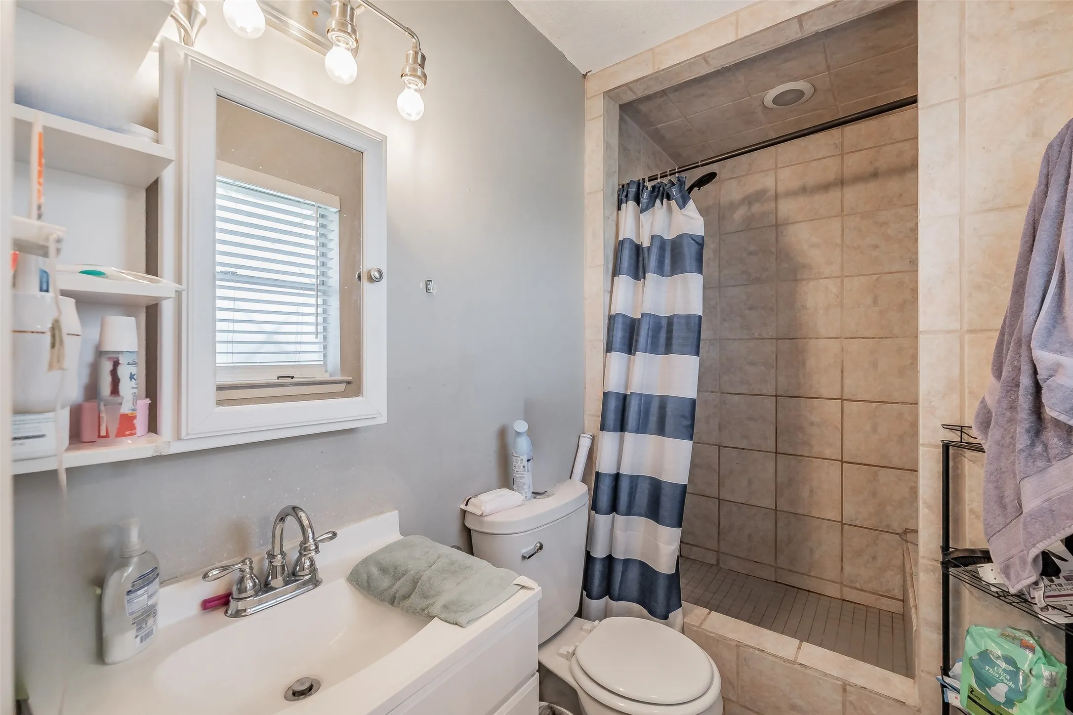 Primary bathroom featuring a tiled shower enclosure, updated vanity and a mirrored medicine cabinet.