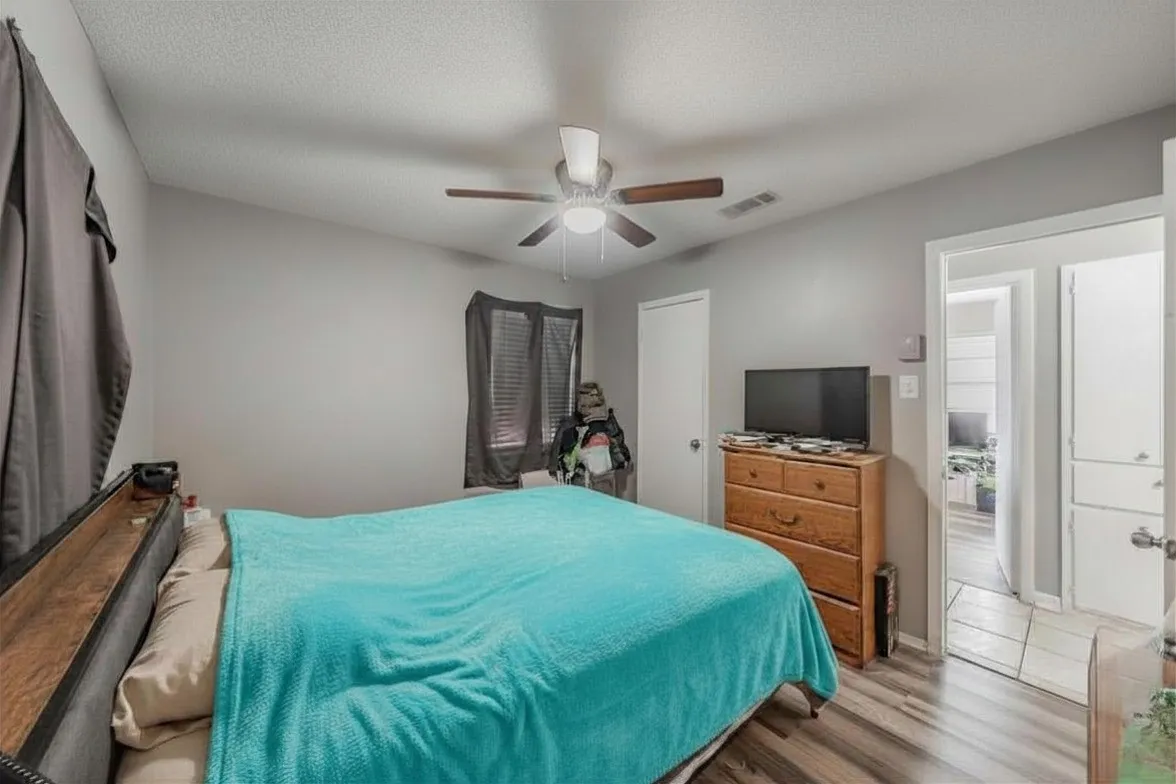 Primary bedroom featuring vinyl wood look floor, ceiling fan and full en-suite bathroom.