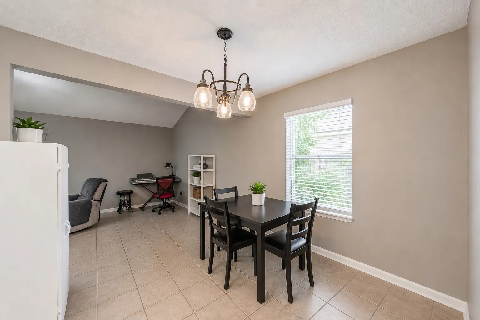 Dining room featuring neutral tile flooring and a decorative chandelier. Photo has been digitally enhanced.