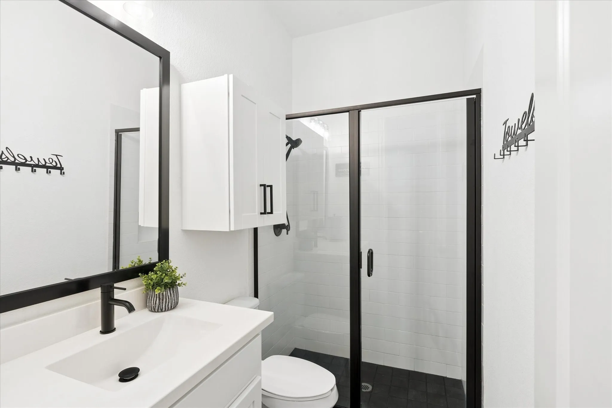 Modern bathroom featuring a rectangular vanity sink with a matte black faucet, a large framed mirror, and a walk-in shower with a glass enclosure