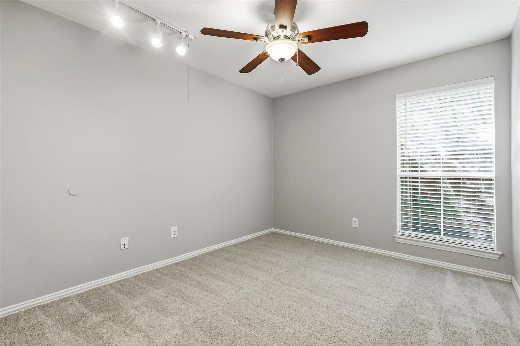 Bedroom featuring neutral gray walls, light-toned carpet, white trim, a ceiling fan with light fixture, and a window with blinds