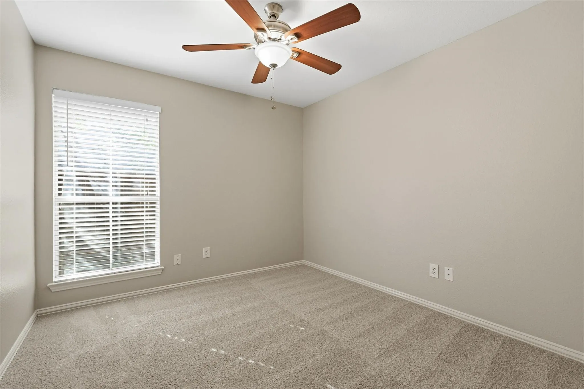 Room featuring neutral carpeting, a large window with horizontal blinds, and a ceiling fan with integrated lighting